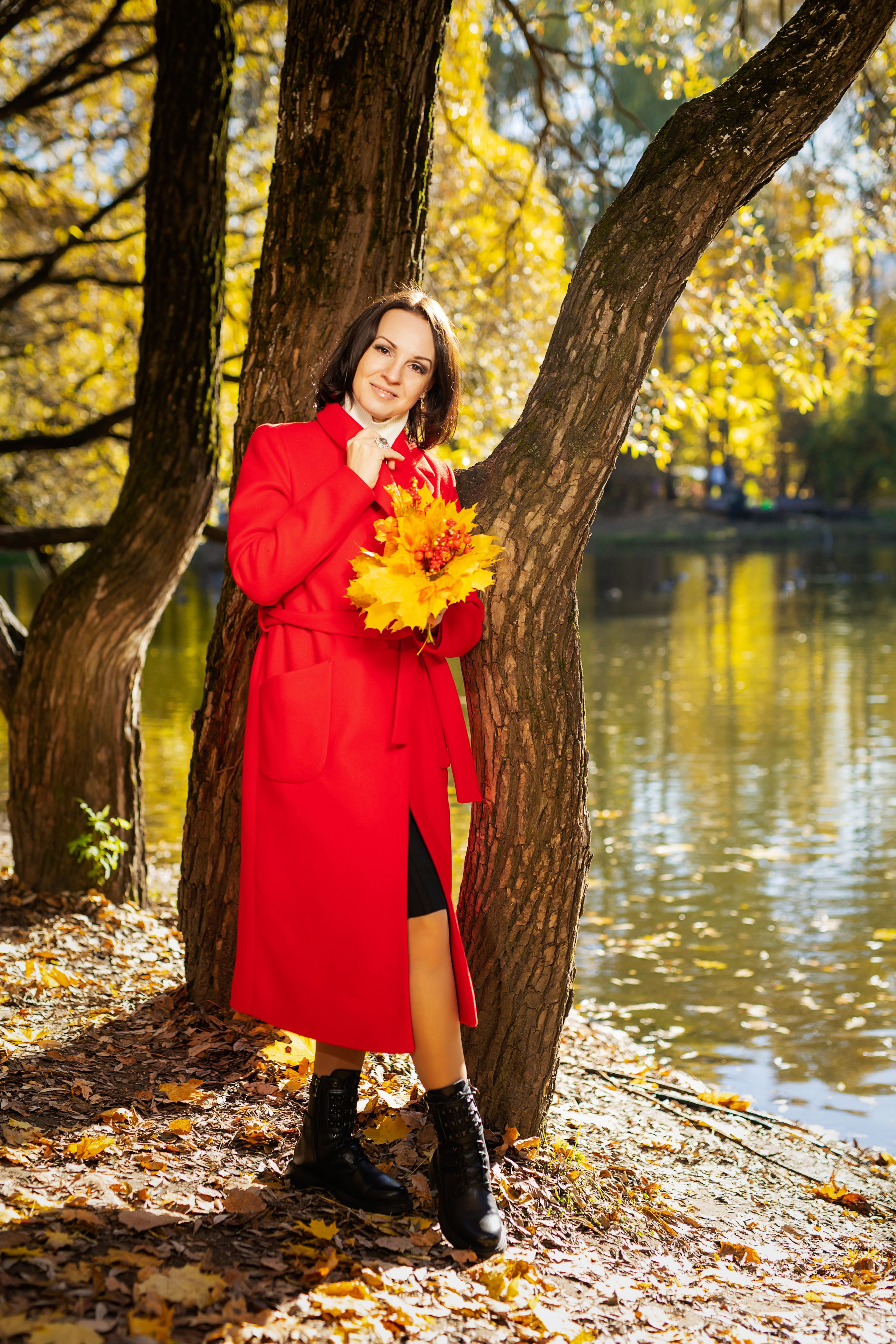 Девушка в красном пальто с красивым букетом осенних листьев