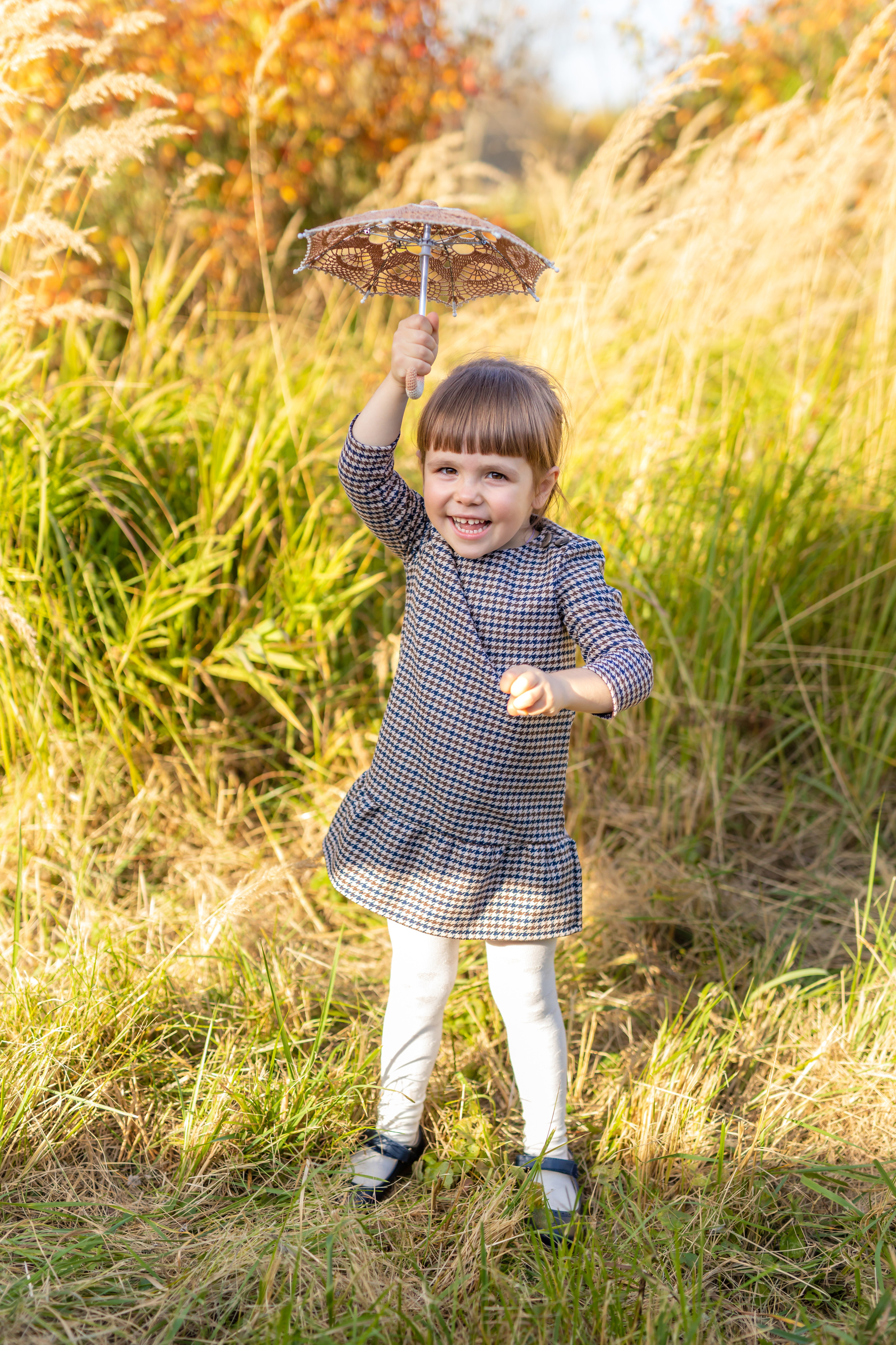 Счастливая девочка играет в осеннем парке, детская осенняя фотосессия