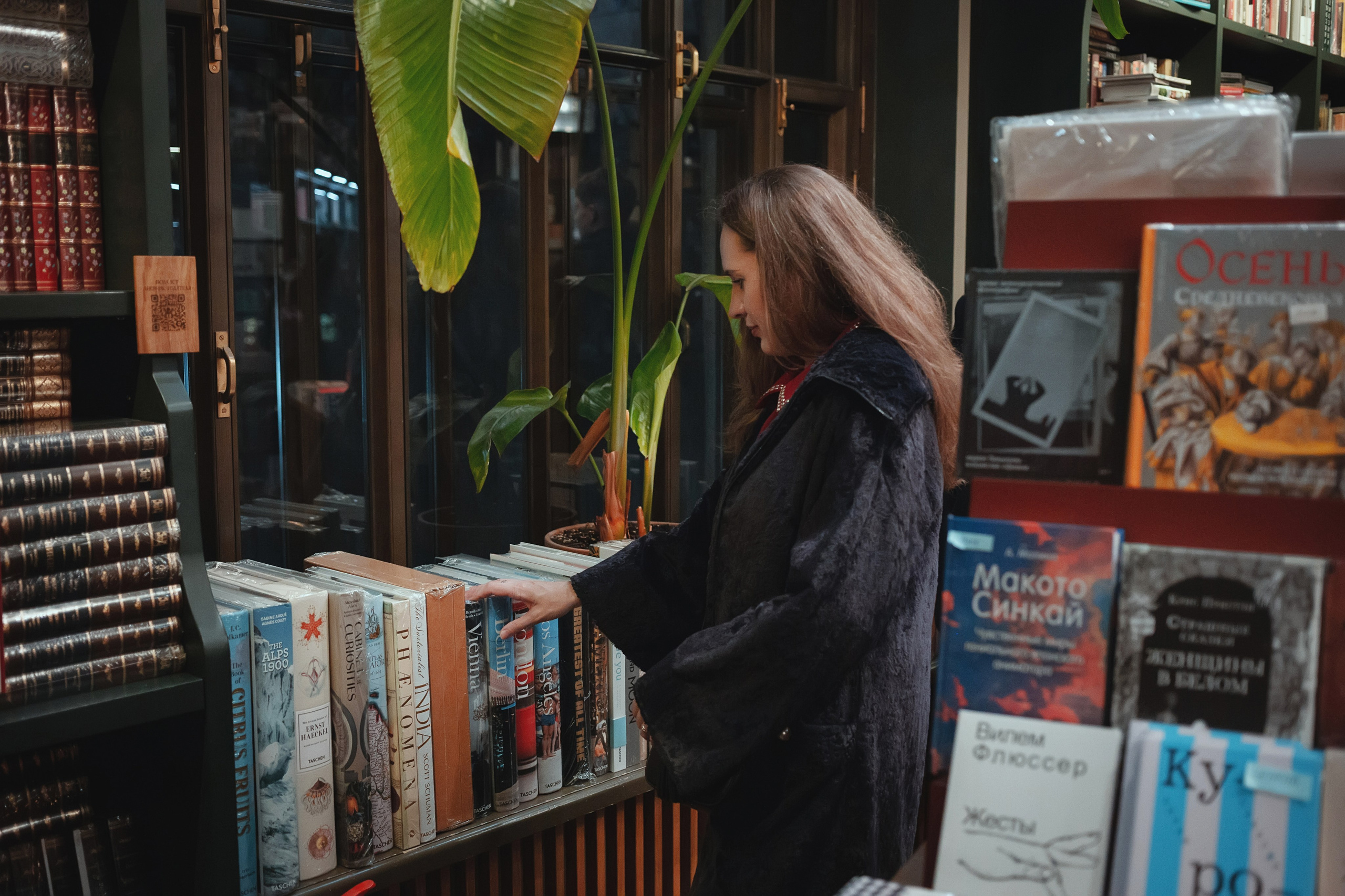 Съемка в книжном магазине в СПб, женщина выбирает книгу, локации для фотосессии