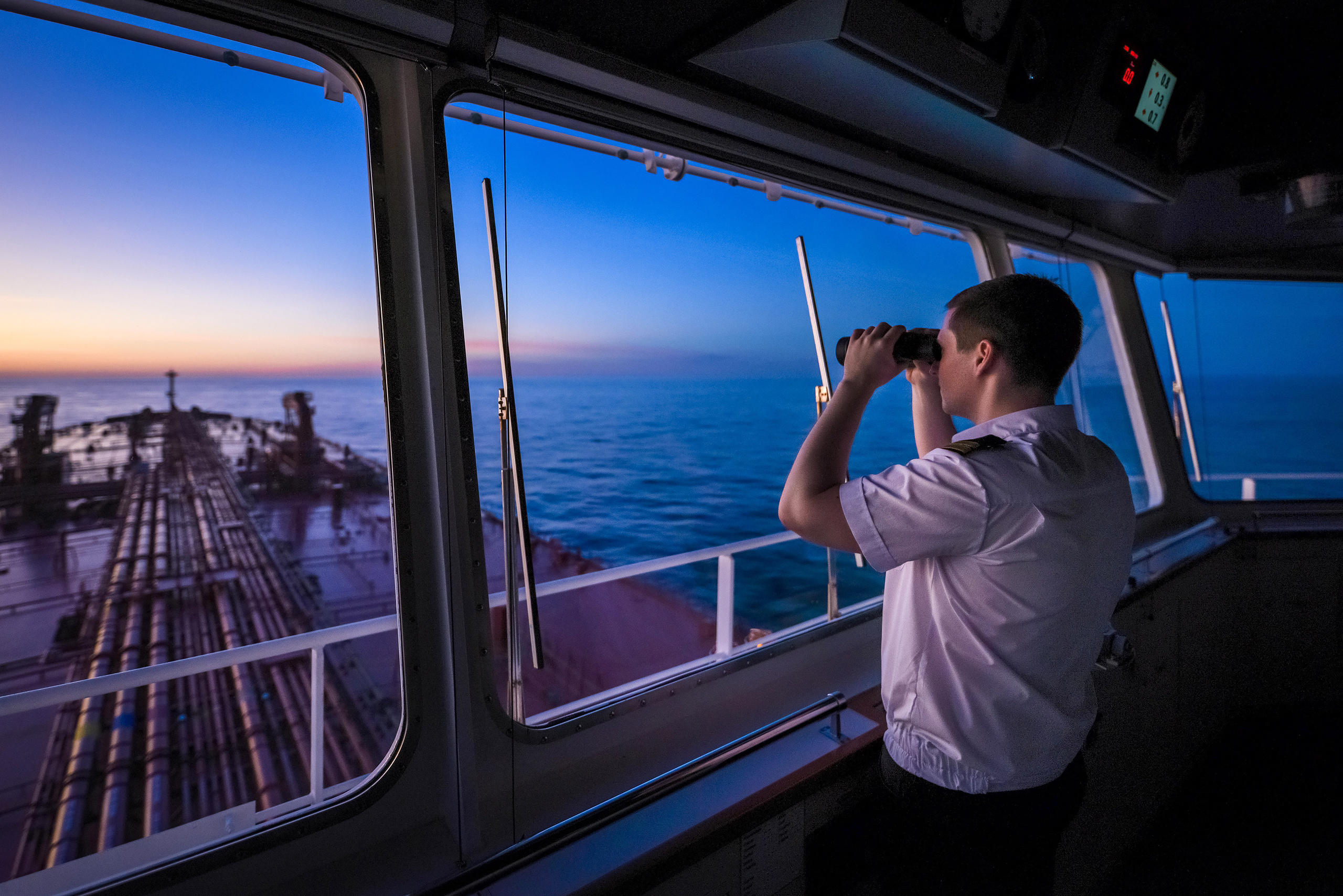 Второй офицер на вахте на навигационном мостике, смотрит в бинокль
