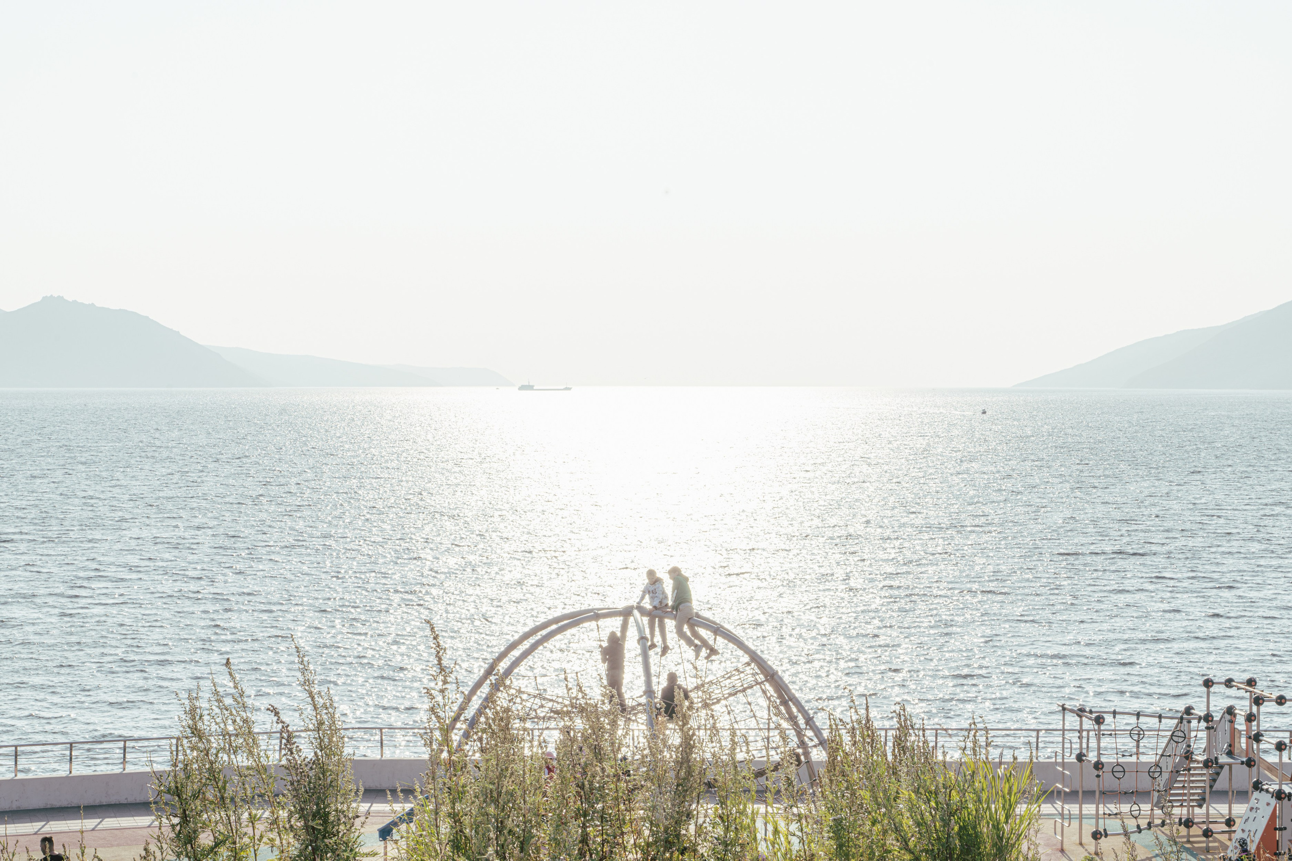 В Магадане и других удаленных регионах Дальнего Востока всю остальную часть России называют "материком" из-за географической изоляции. Магадан расположен на побережье Охотского моря, окруженный горами и труднодоступными территориями. Добраться туда можно только по воздуху, морю или опасной Колымской трассе, что создает ощущение оторванности от "большой земли". Это исторически сложившееся выражение подчеркивает как физическую, так и культурную дистанцию между регионом и центральной частью страны. По другой версии, первые заключенные, которых привозили на кораблях, после нескольких недель в море думали, что их высадили на большом острове.