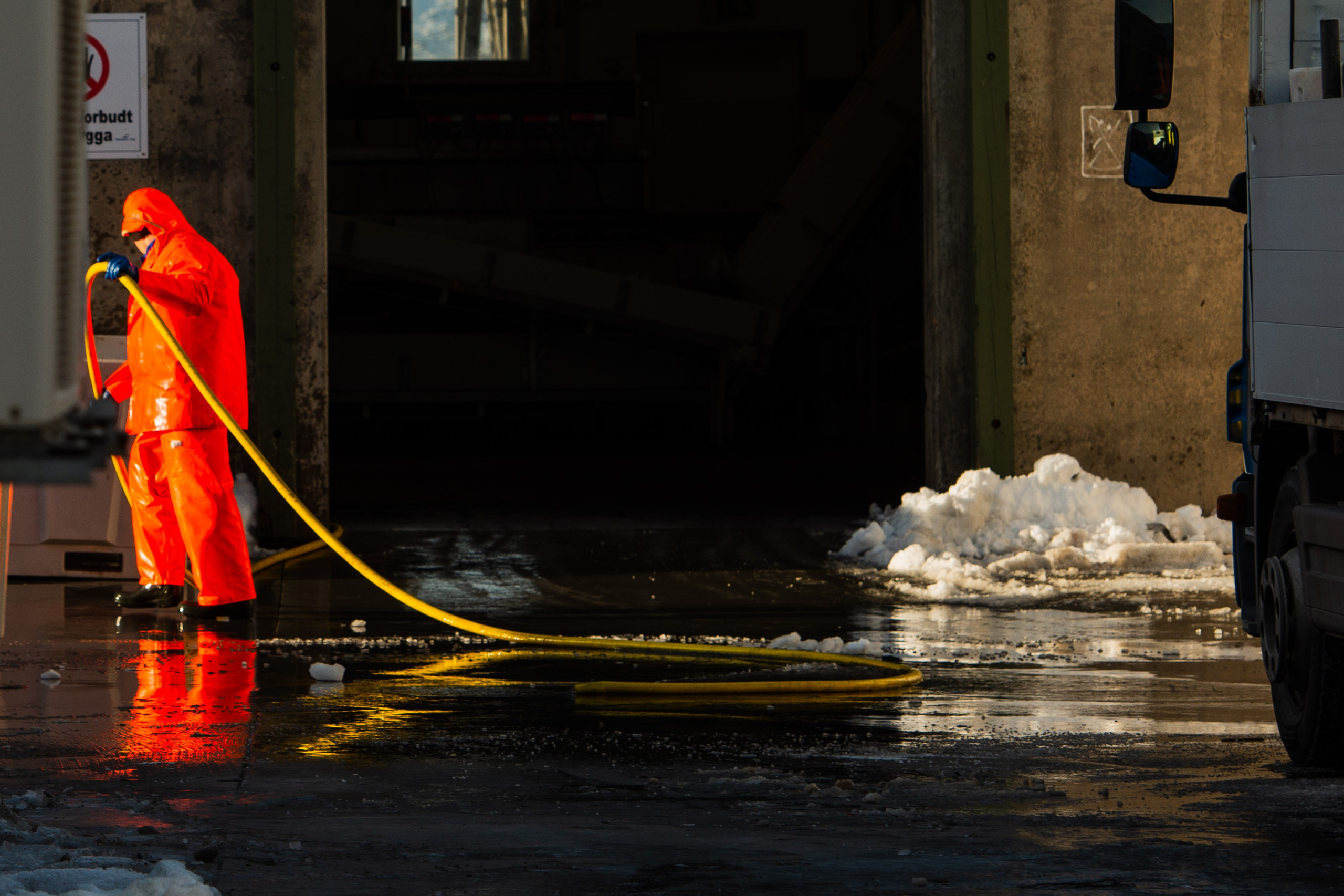 Fisherman worker in an orange protective suit at a Lofoten fish factory — северная индустрия и контрастные цвета.