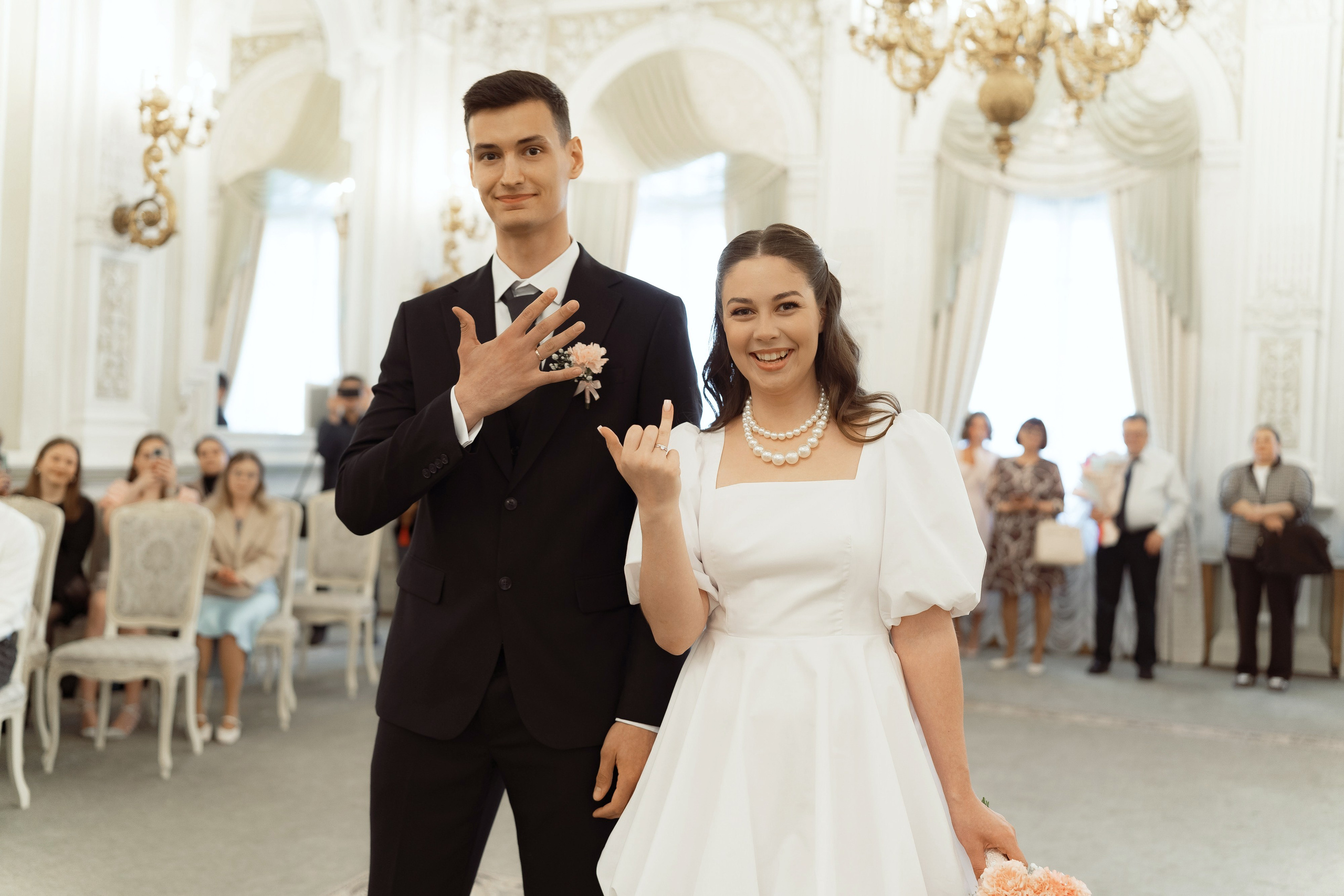 Молодожёны показывают кольца гостям после официальной регистрации брака