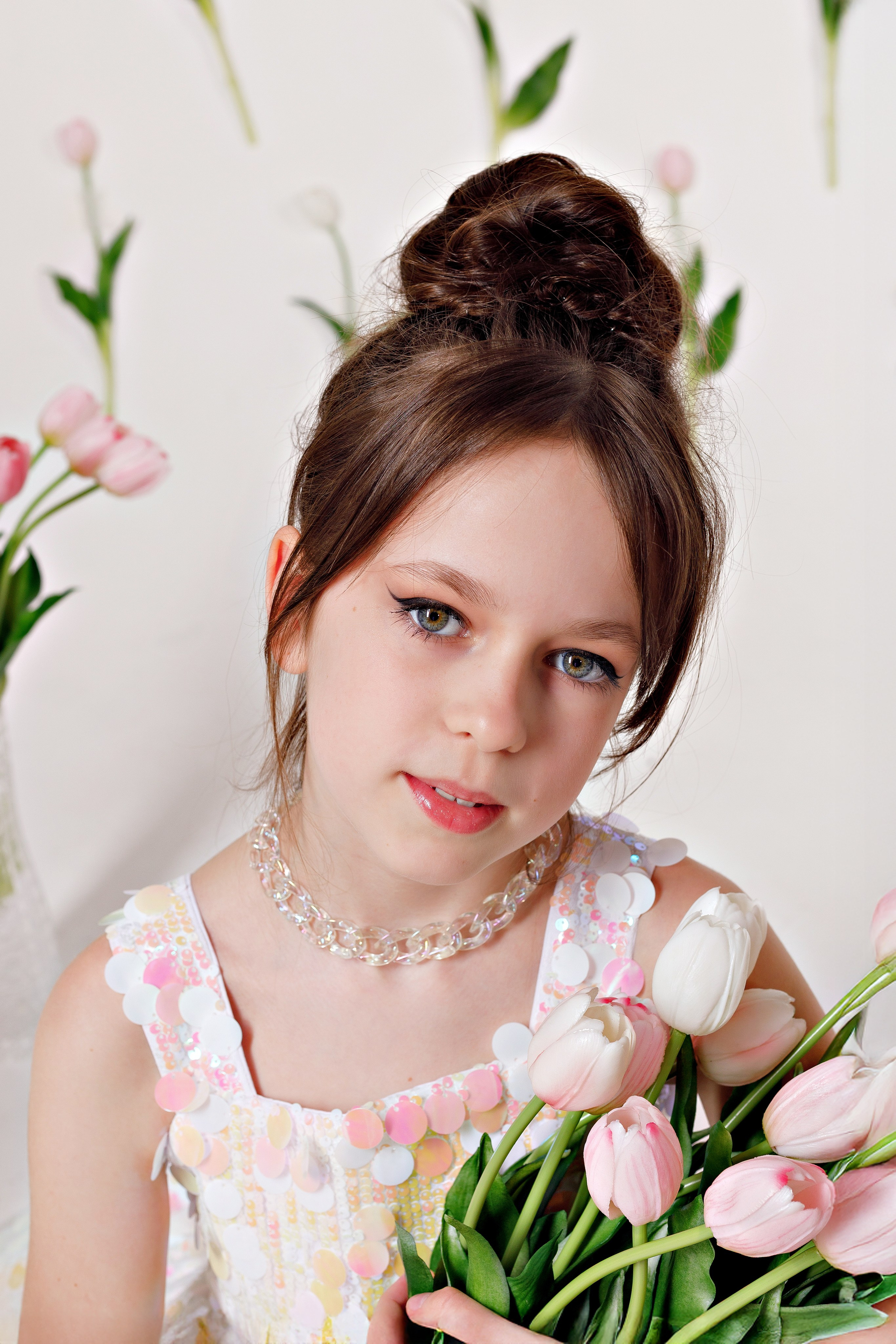 Соня в нарядном платье с тюльпанами, улыбается на фоне праздничной фотозоны в Сочи