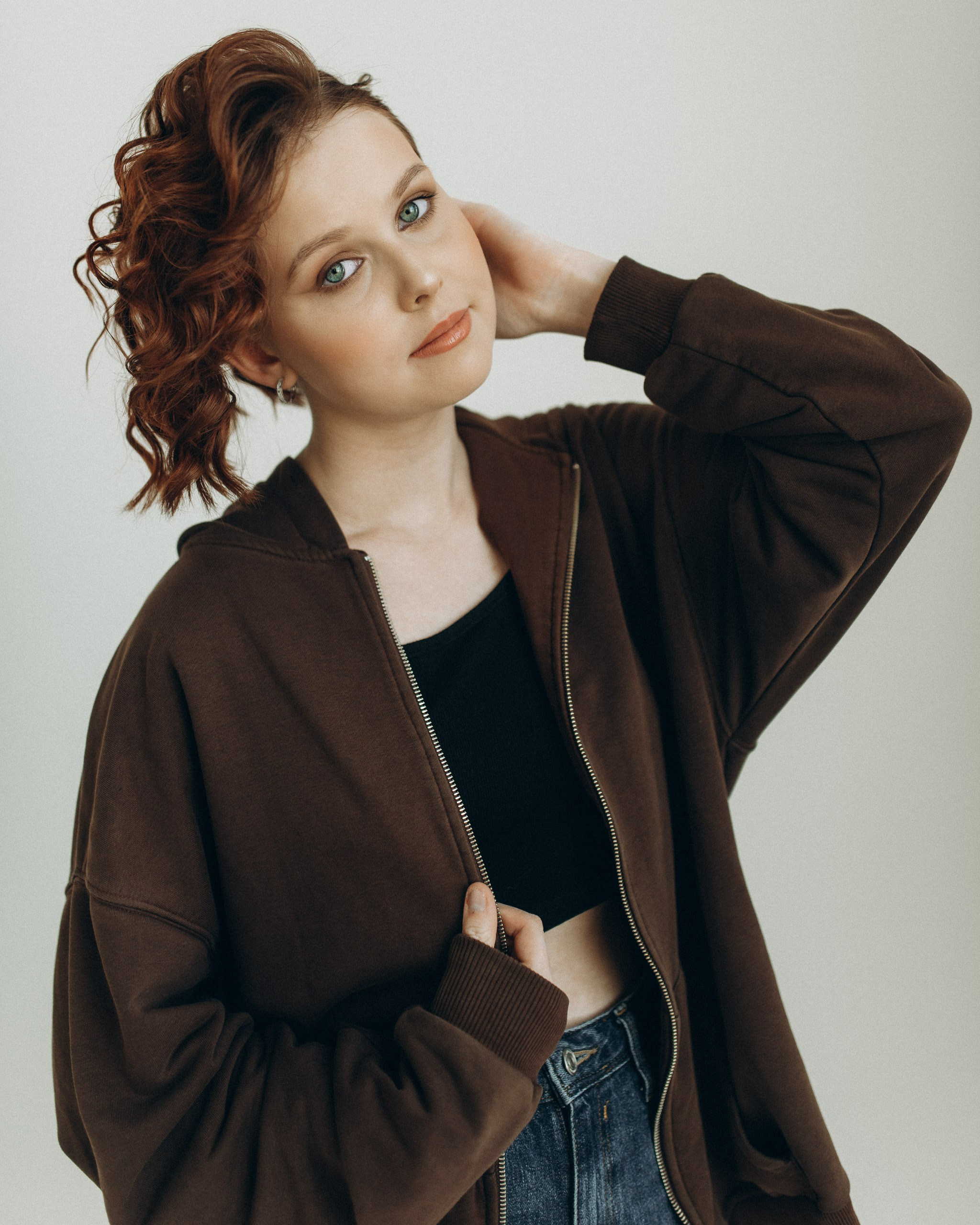 Подростковый портрет девушки с рыжими вьющимися волосами в коричневой зип-худи. Студийная фотосессия в Новосибирске, подарок на 15 лет