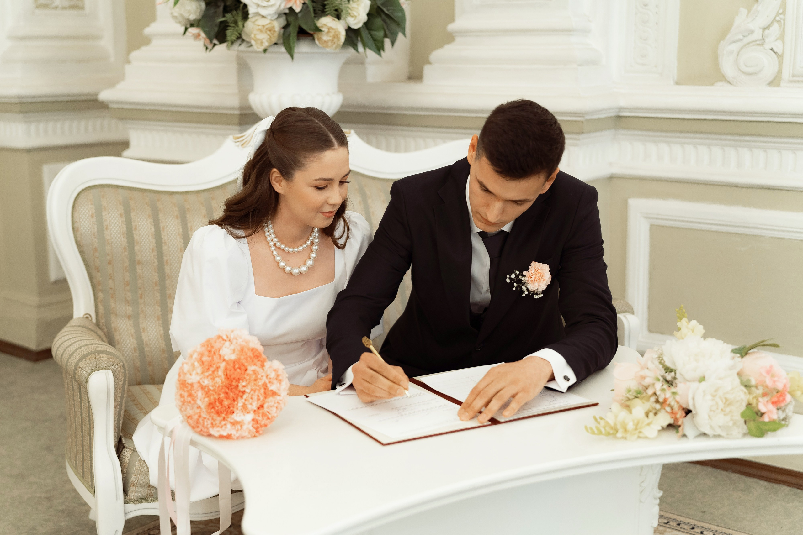 Жених и невеста ставят подписи в книге регистрации брака, торжественная свадебная церемония
