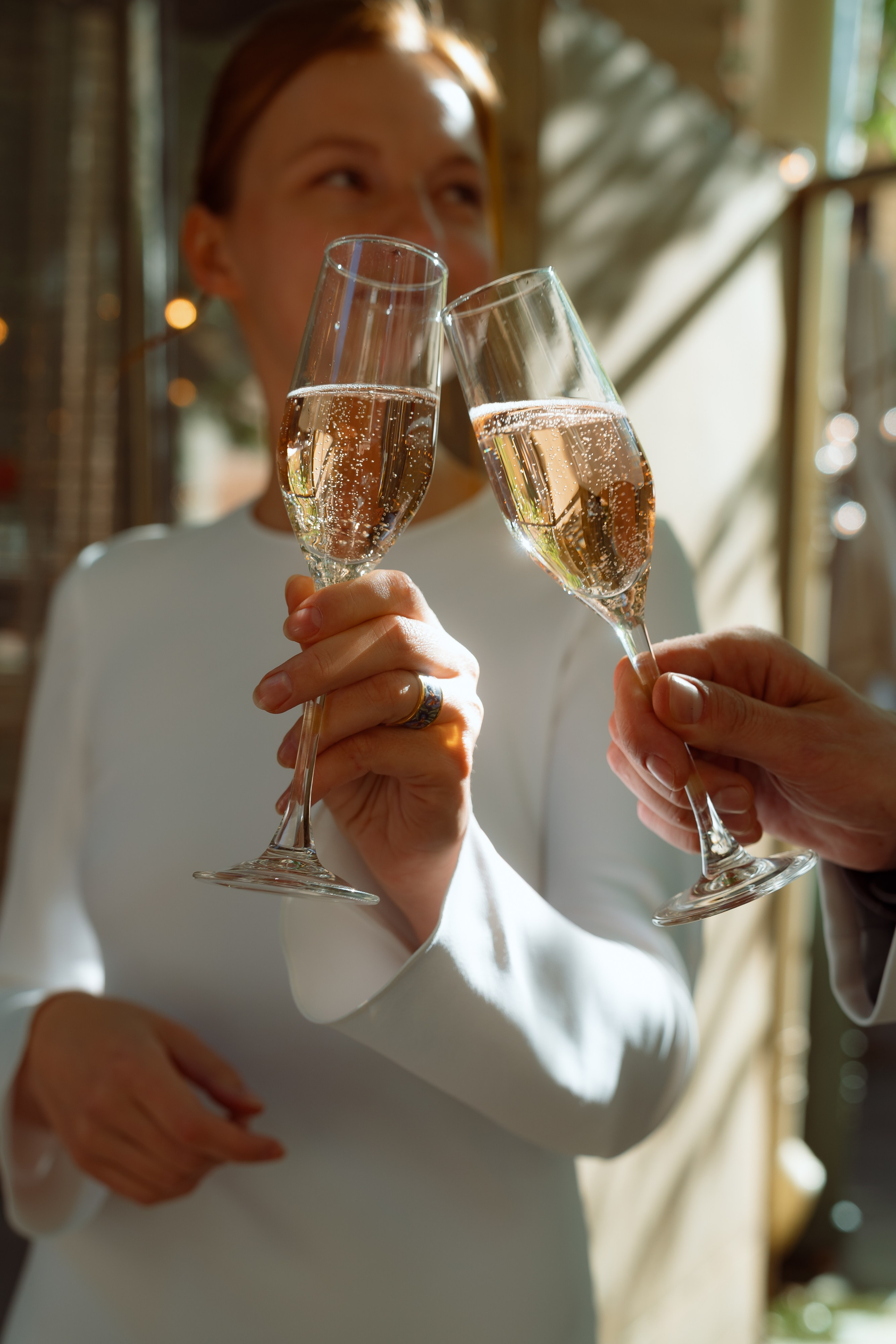 Мария и Евгений чокаются бокалами просекко, золотые блики