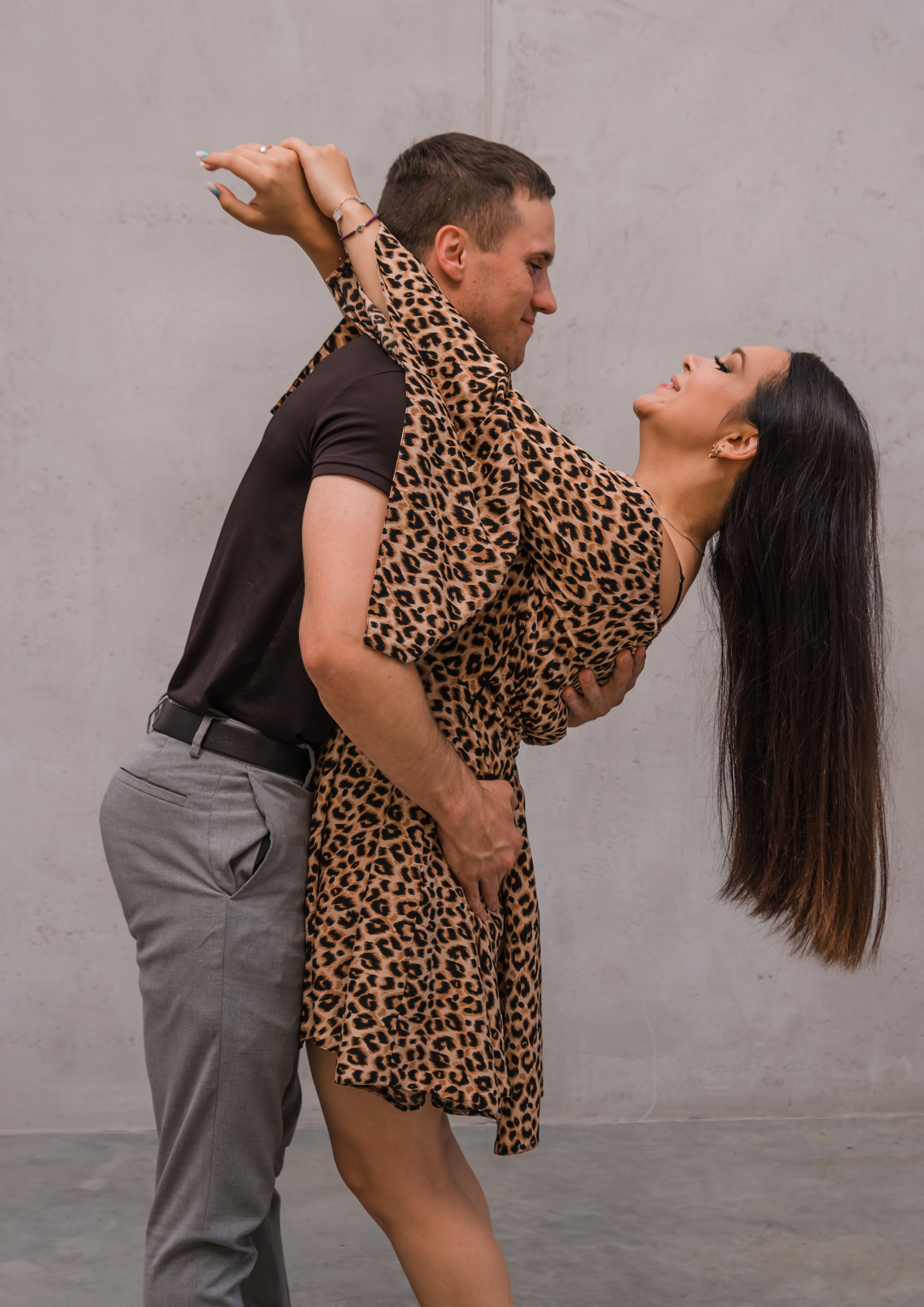 На фотографии семейная пара в полный рост обнимают друг друга.