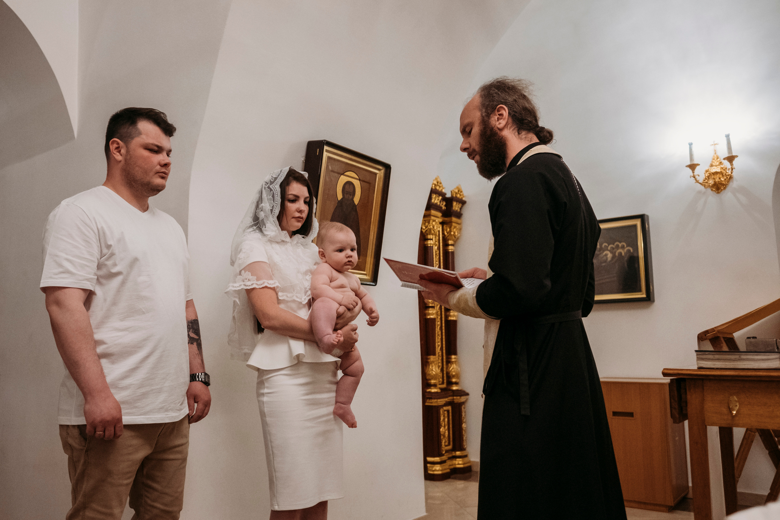 Чтение молитв в крестильной комнате во время таинства крещения.
