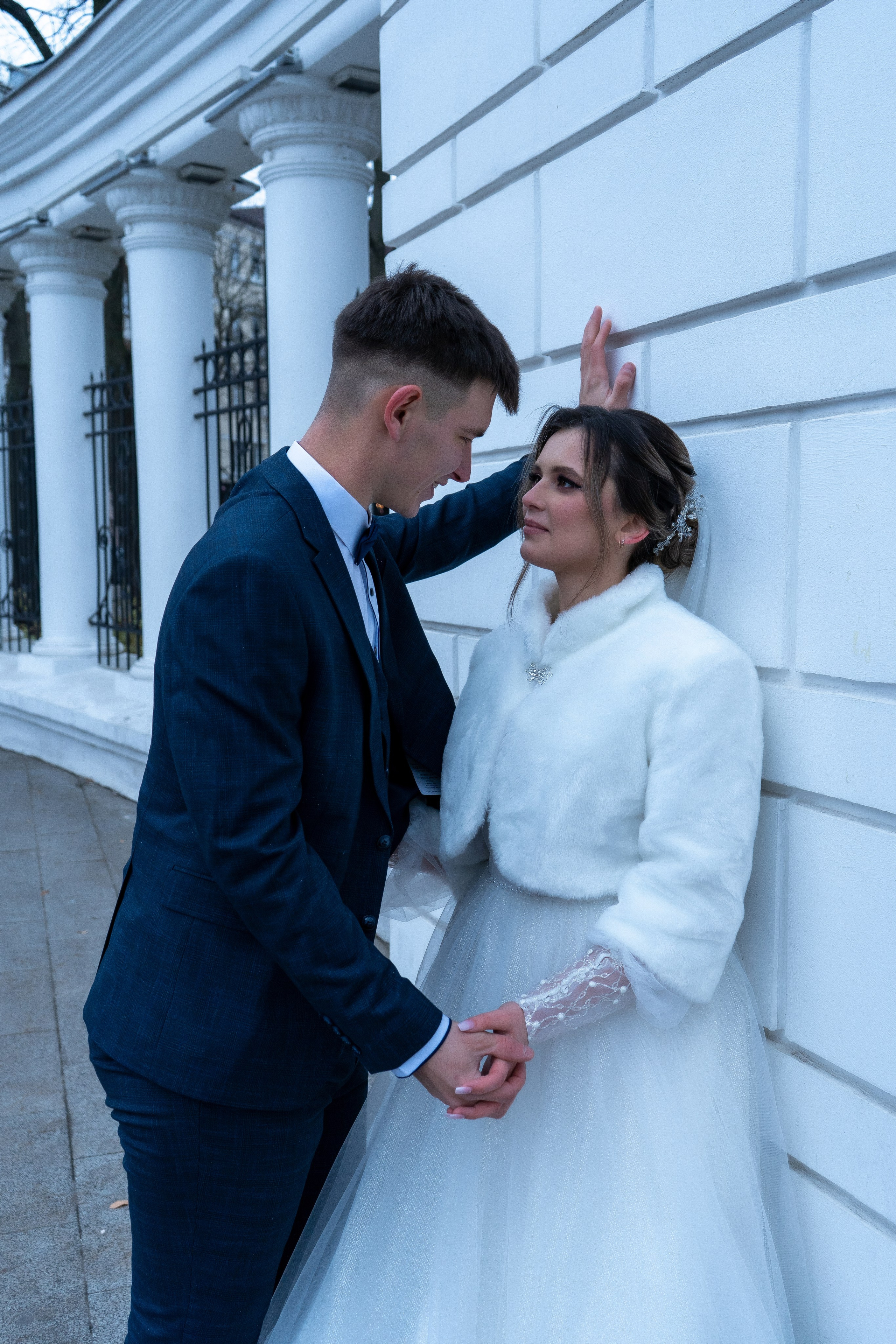 На фоне белых колон парка Орленок, жених смотрит на невесту