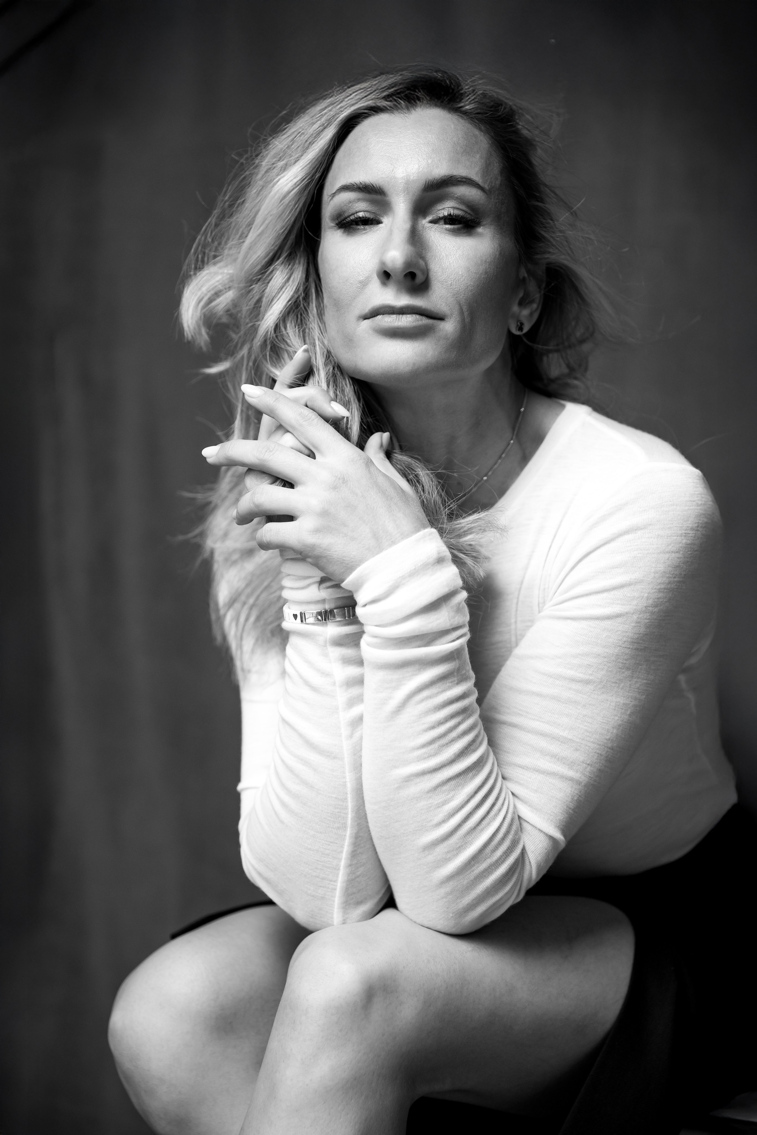 Чёрно-белый художественный портрет женщины в студии, естественная поза, мягкий свет, нейтральный фон