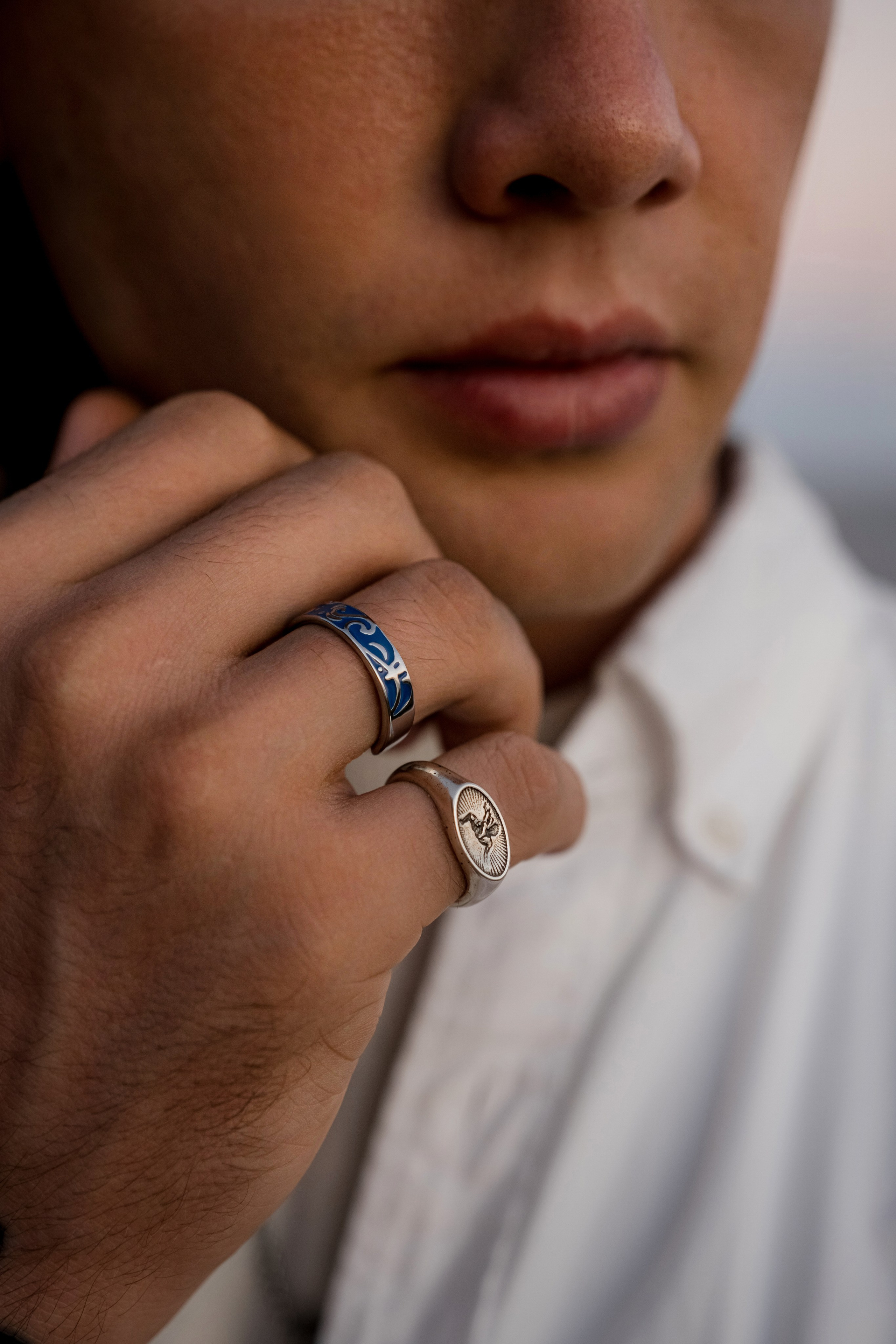 Close-up of a tattooed hand wearing silver rings, highlighting bold accessory design.