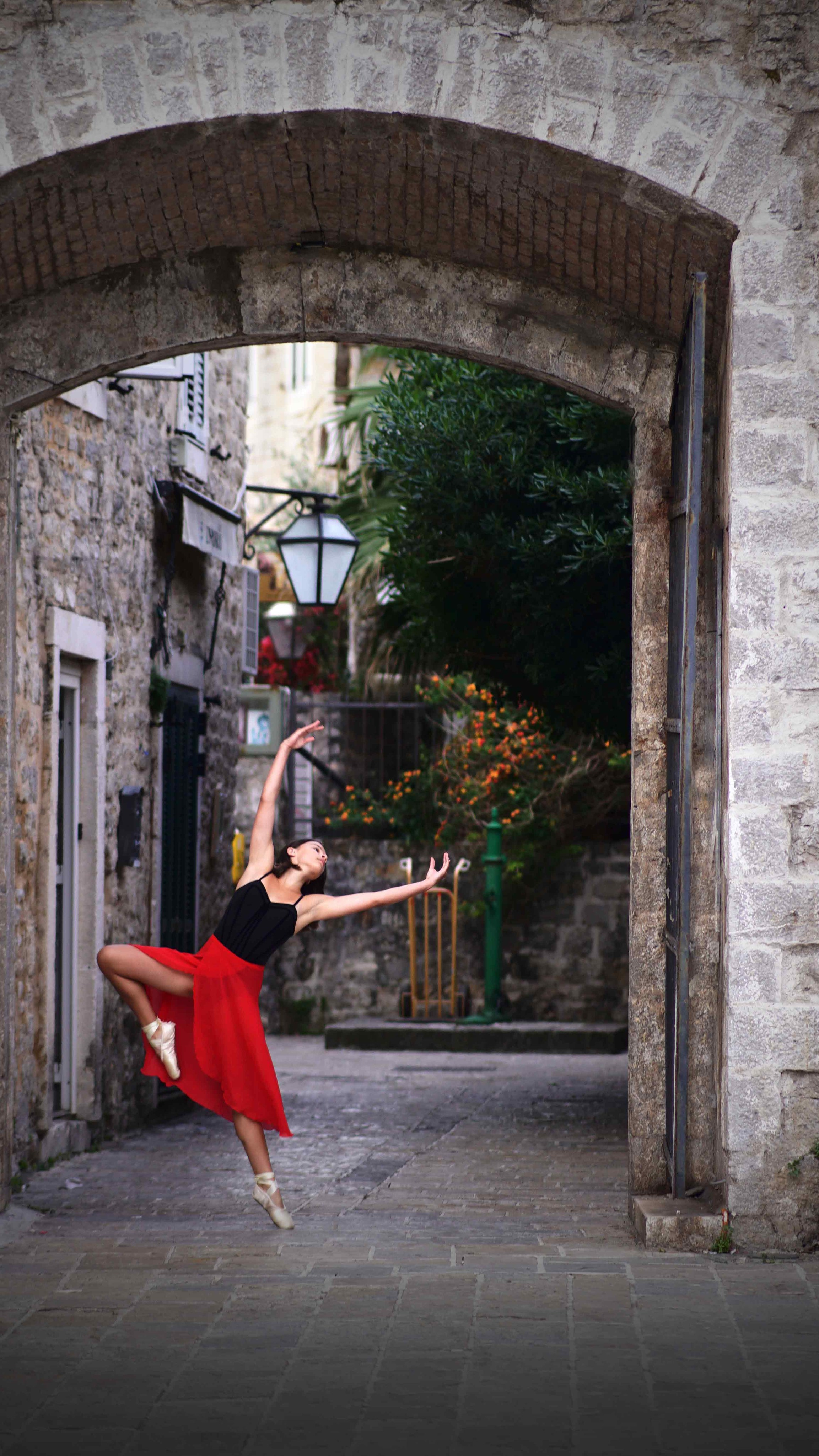 Young ballerina in pointe shoes at sunrise in Budva Old Town