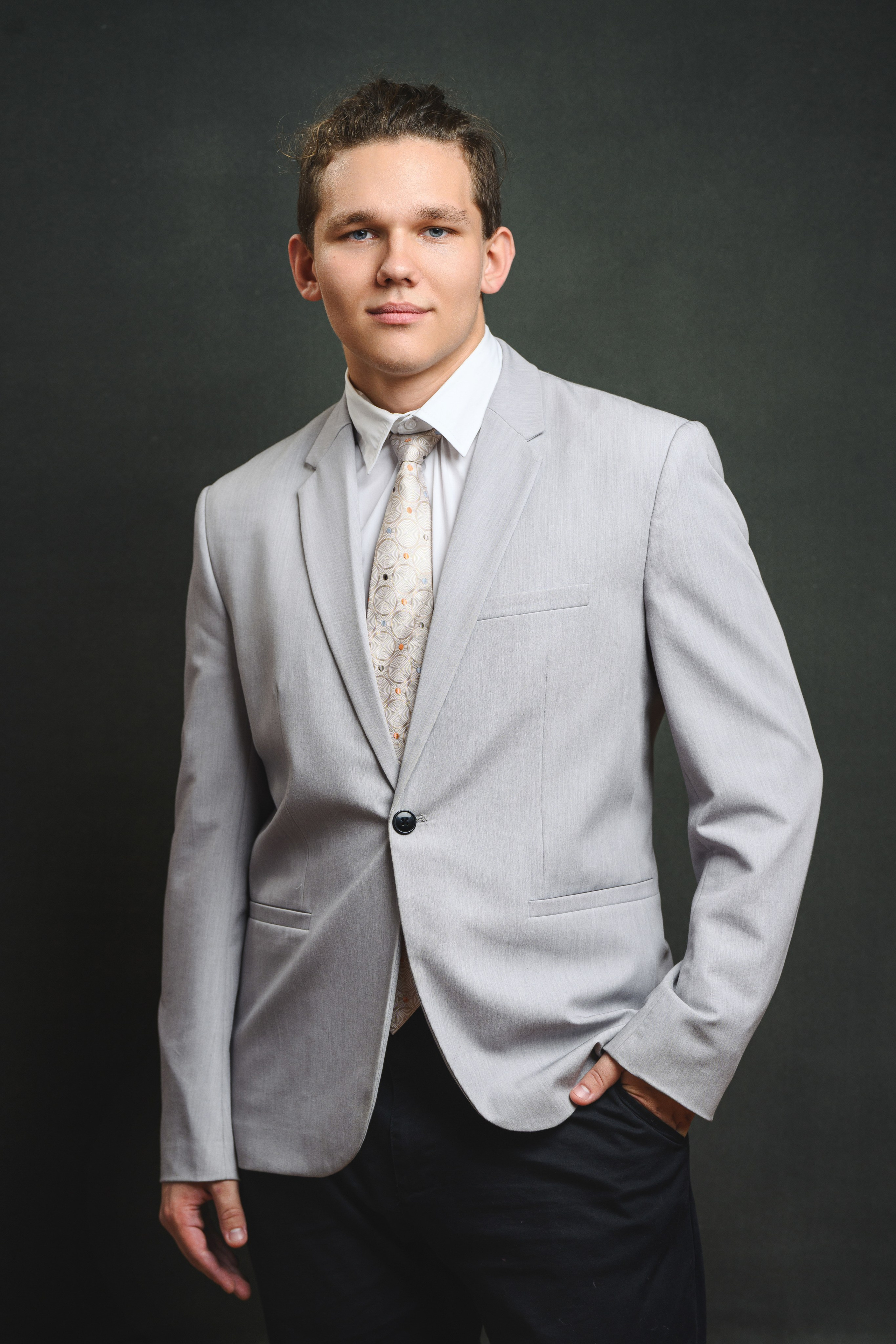 Портрет старшеклассника в светлом костюме и галстуке на тёмном живописном фоне.