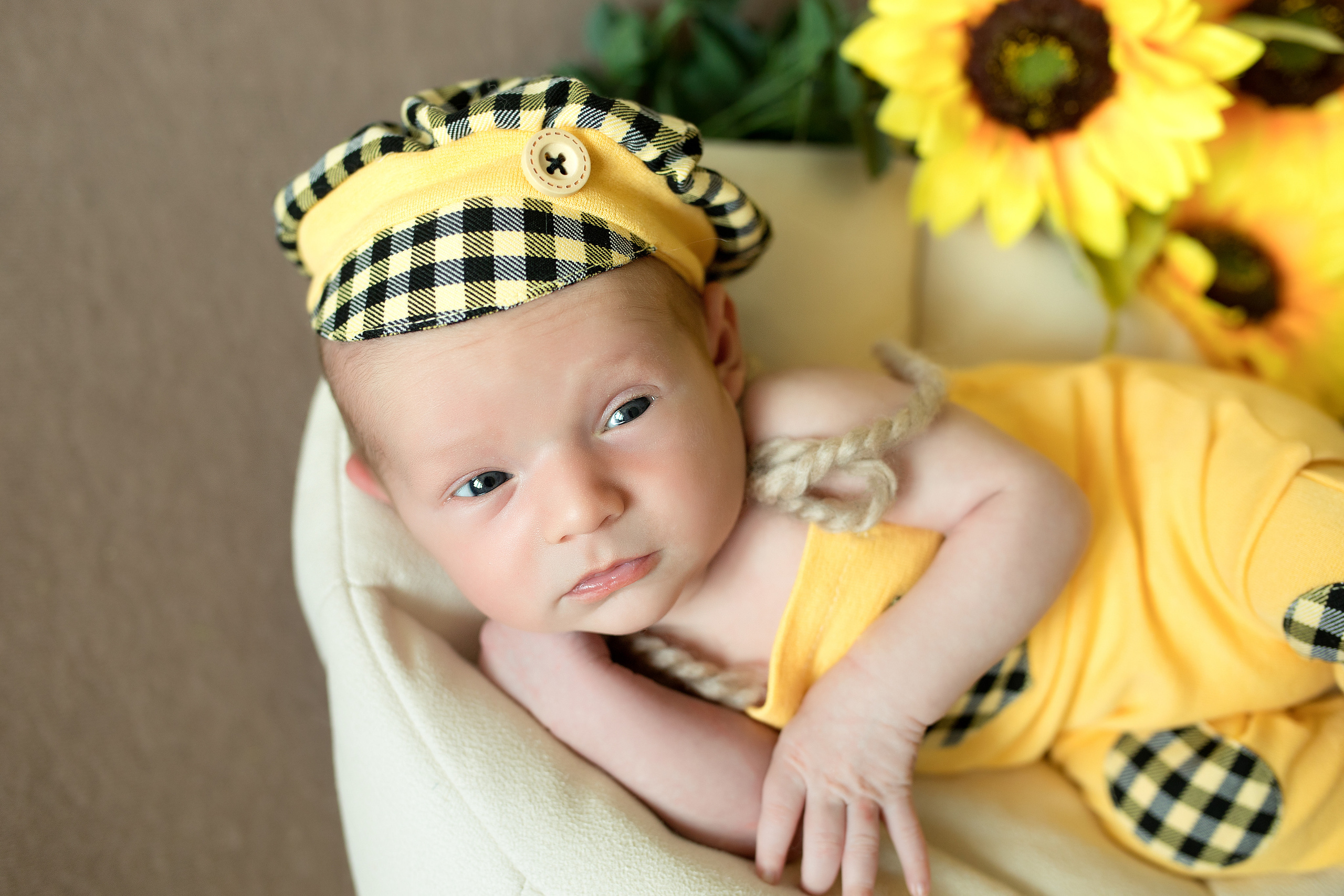 новорожденный мальчик с подсолнухами в желтом костюме с открытыми глазками