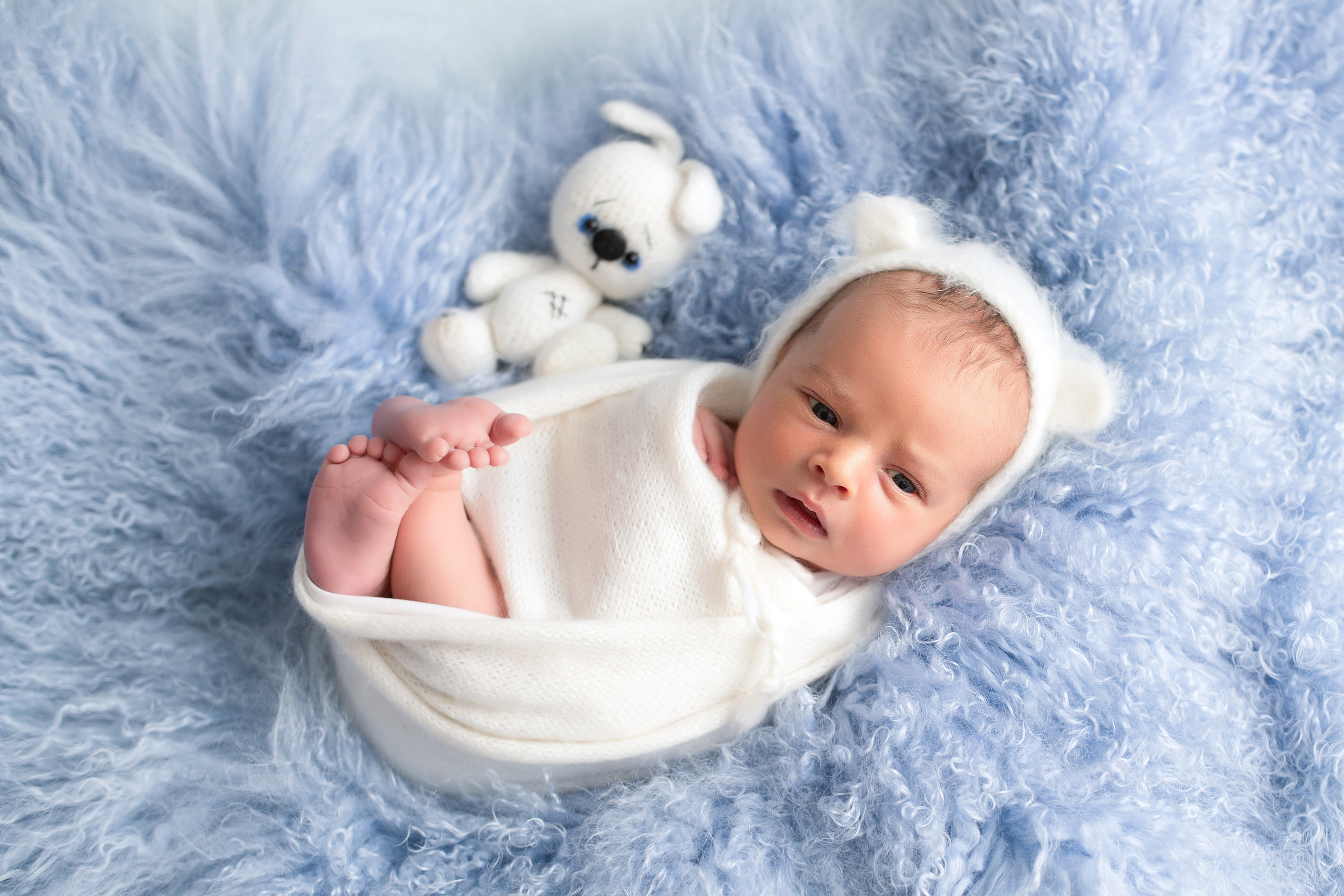 фотография новорожденного в белой обмотке на голубом пушистом фоне
