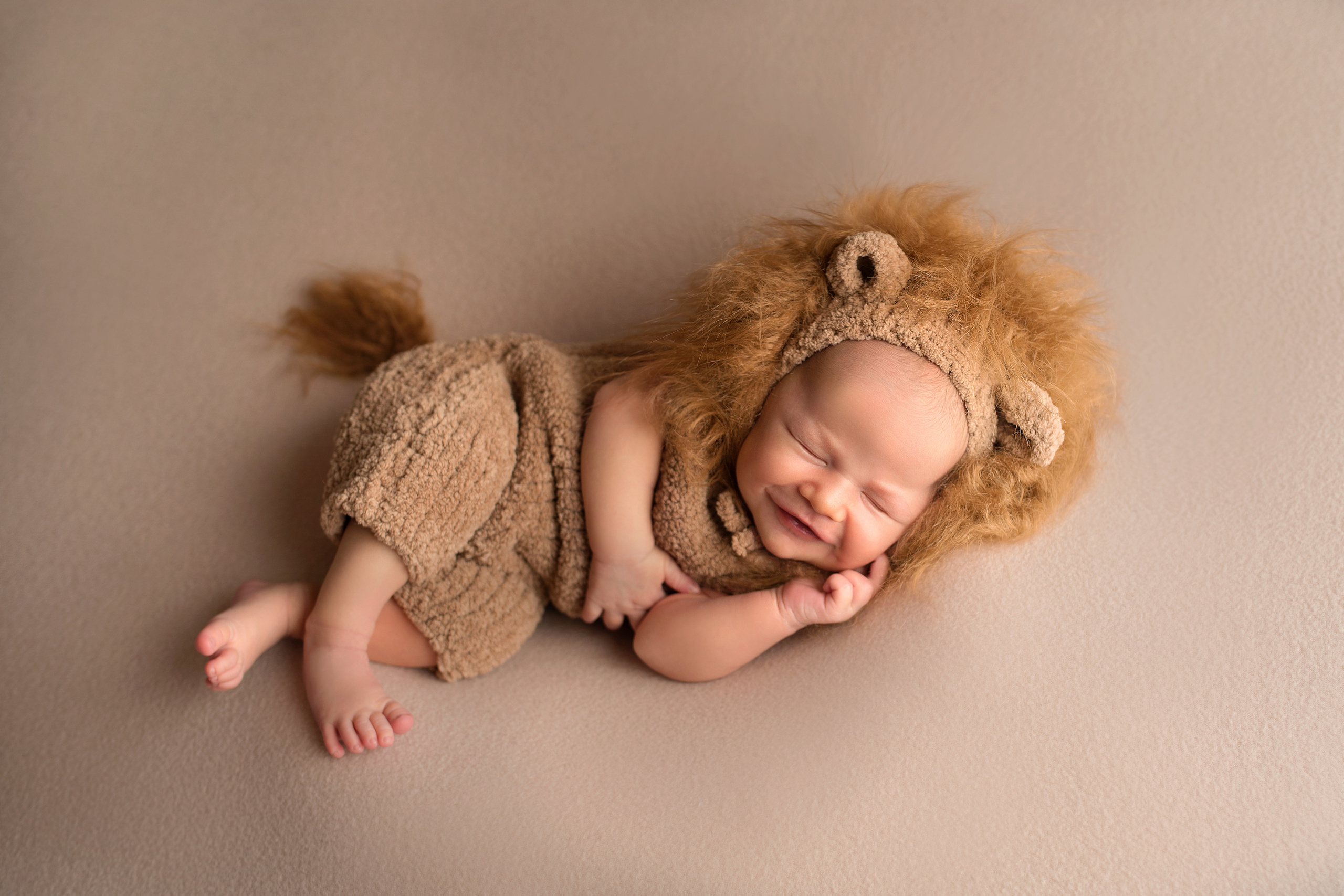 новорожденный малыш в костюме львенка улыбается