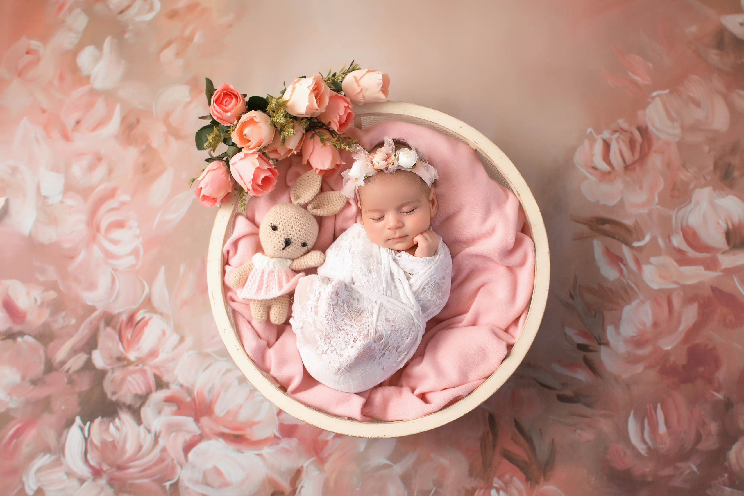 новорожденная на цветочном розовом фоне с цветами в белой обмотке