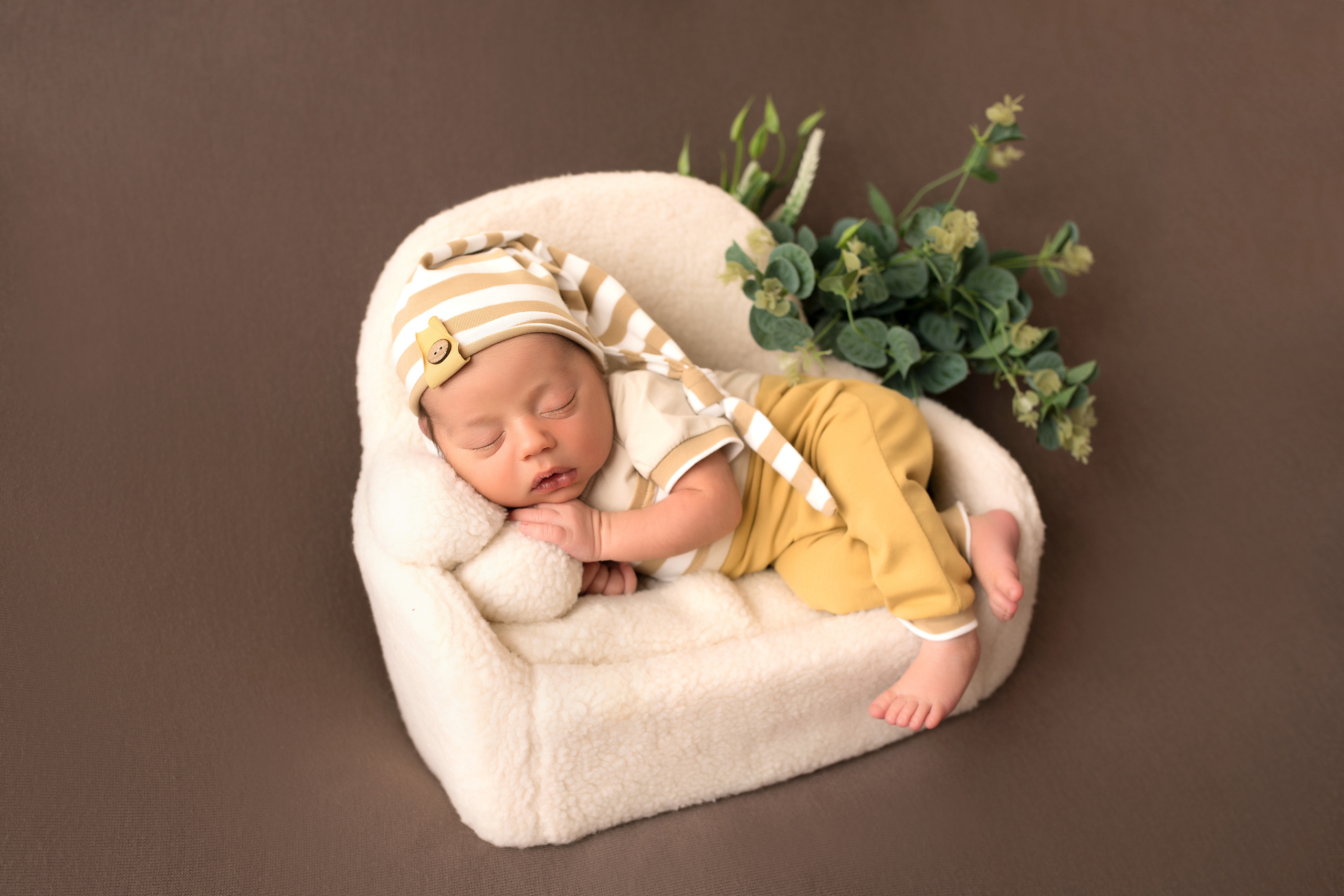 новорожденный в полосатом колпачке на диванчике