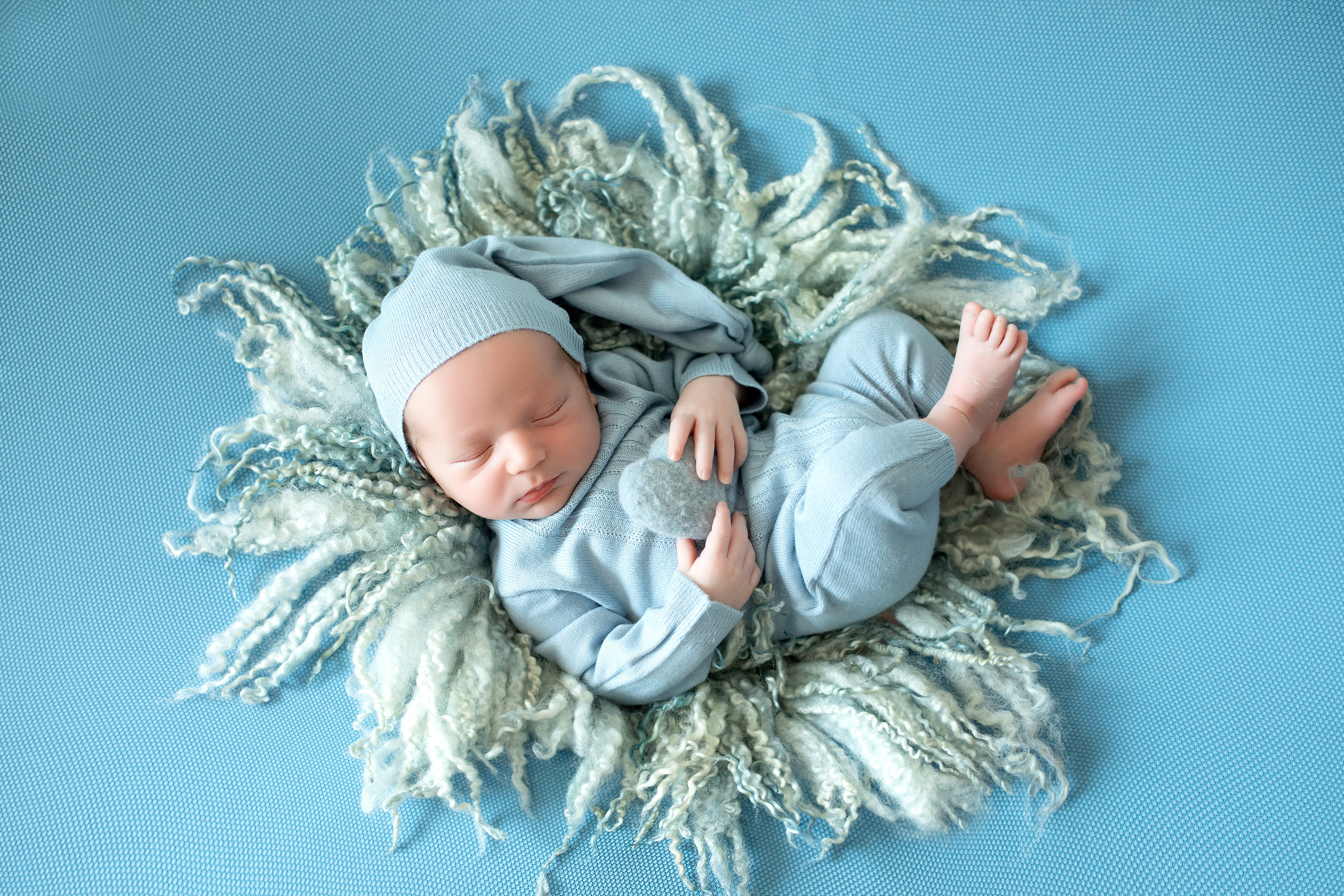 новорожденный мальчик на фактурном коврике в голубом костюме