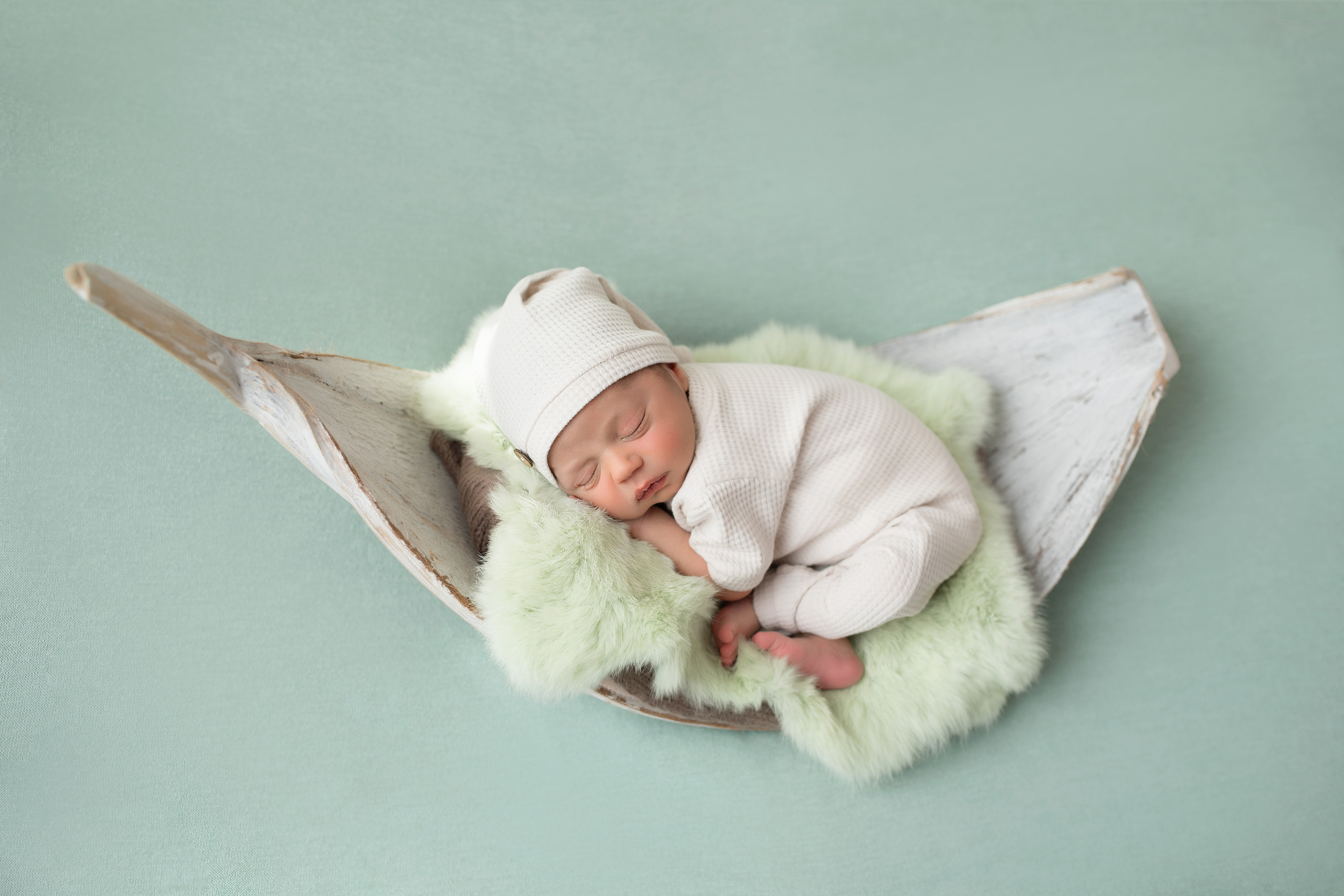 новорожденный малыш на пальмовом листе в мятном костюме на мятном фоне