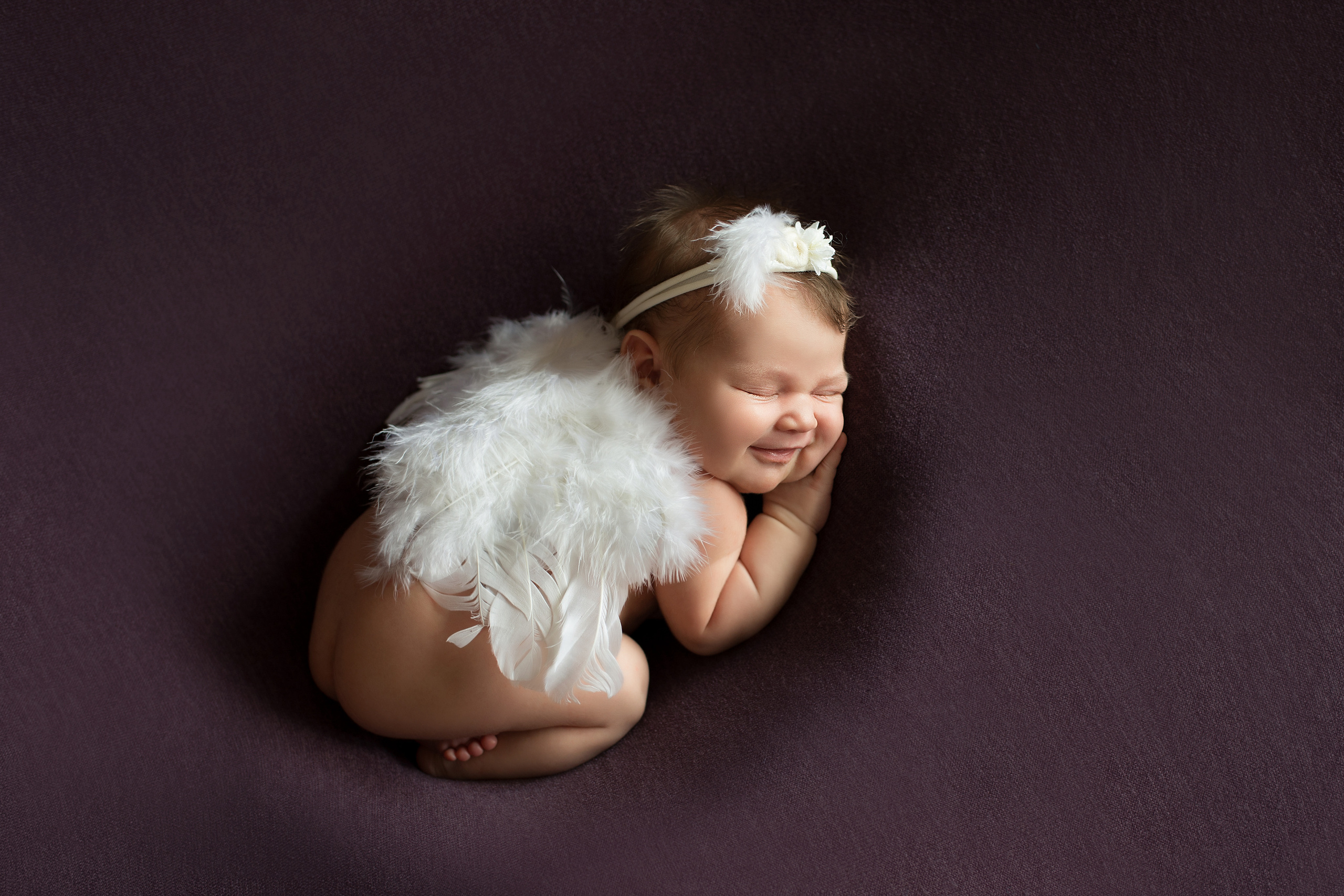 новорожденная девочка с крыльями ангела улыбается