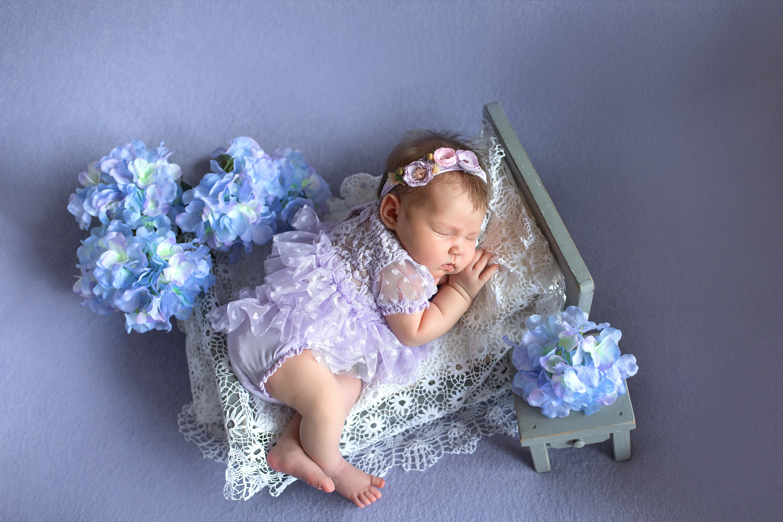 новорожденная девочка на кроватке на лавандовом фоне