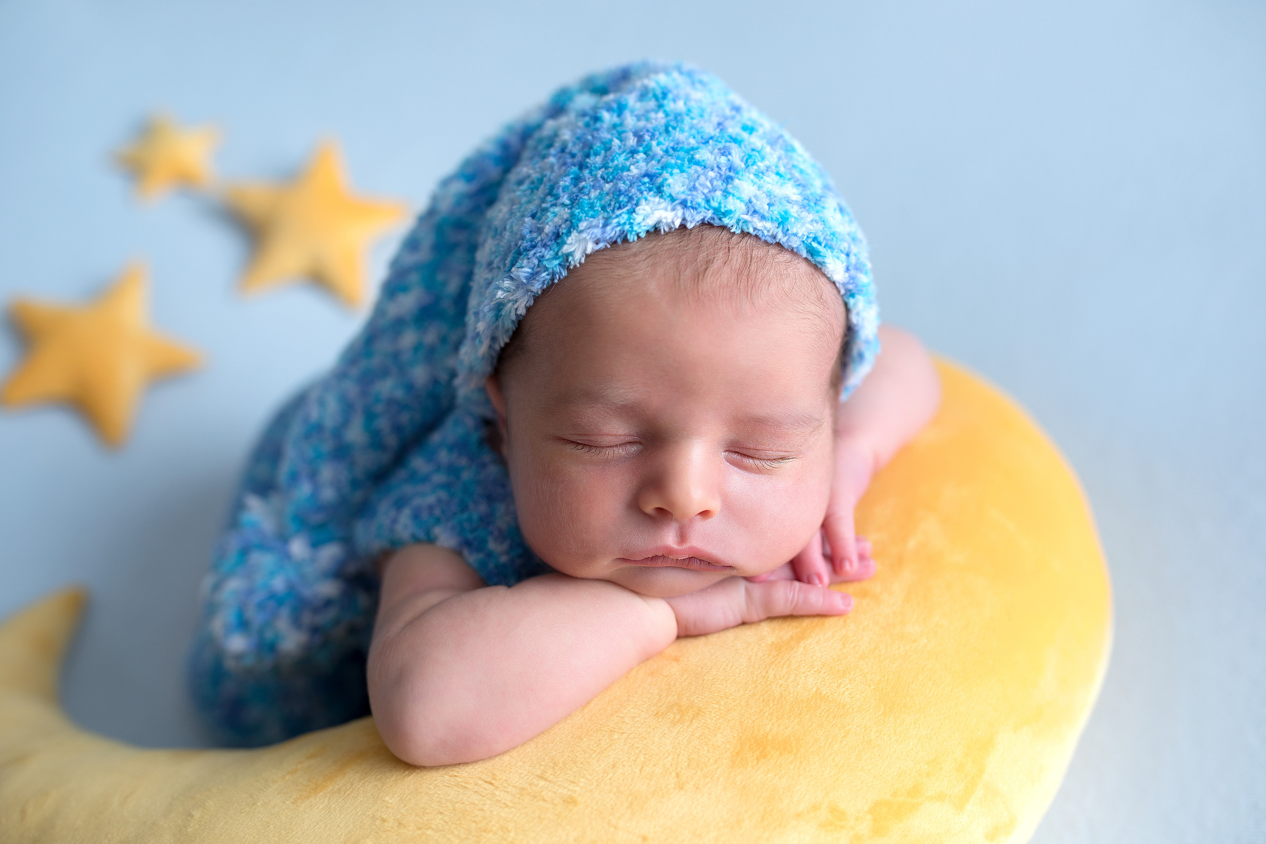 фото новорожденного на желтой луне в голубом колпачке