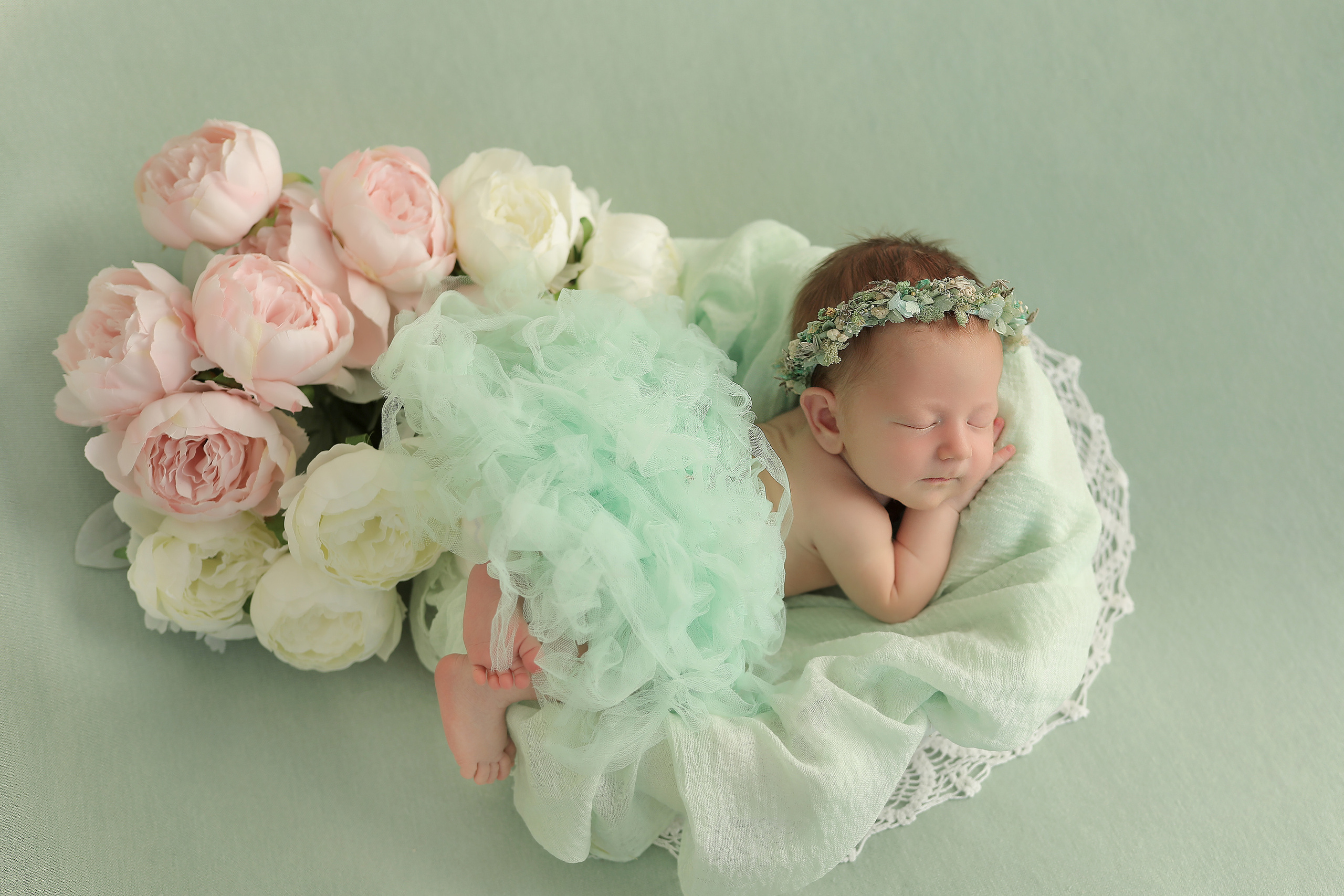 новорожденная девочка в пышной юбке на мятном фоне с розами в веночке