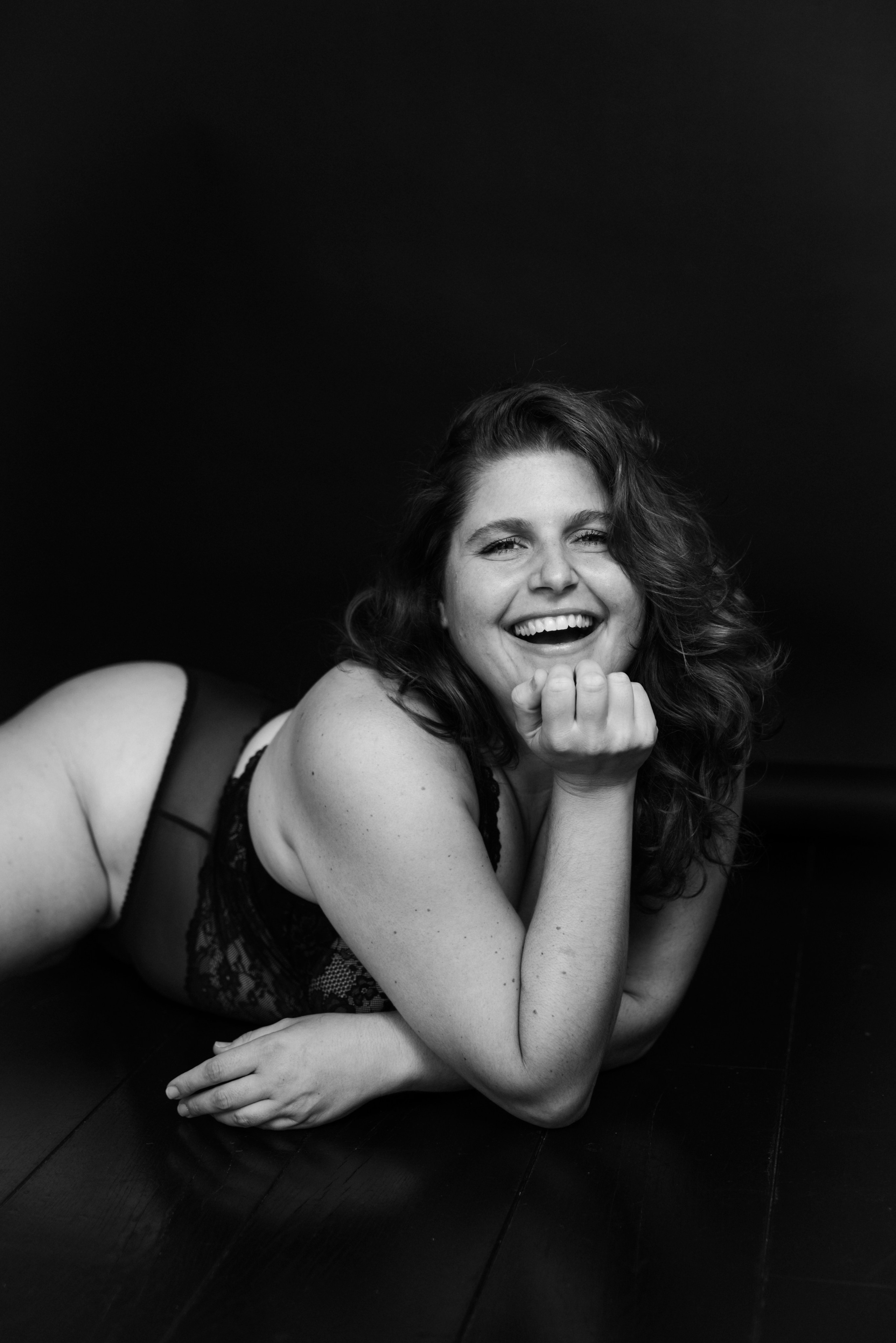 Boudoir photography London — black and white portrait of woman smiling, relaxed pose, empowerment session