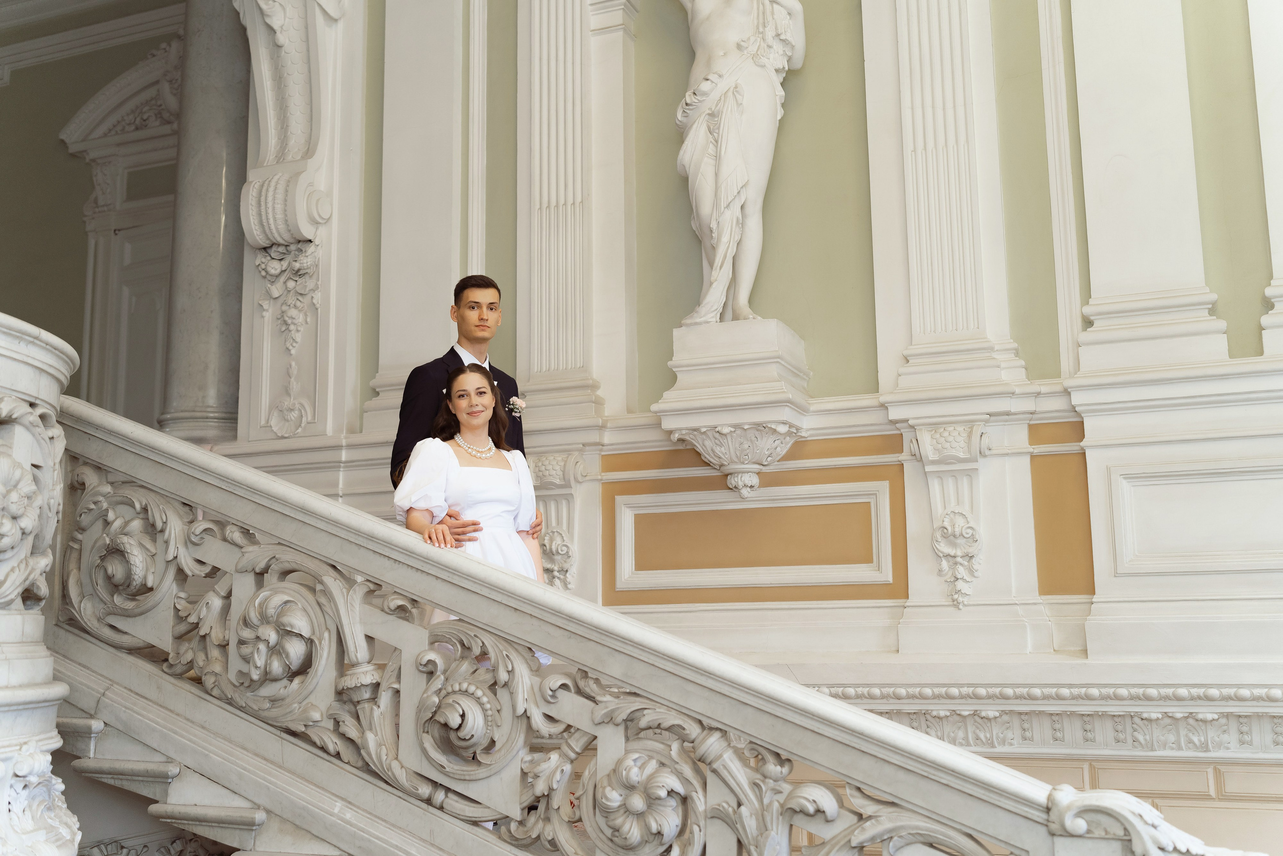 Пара ждёт начала свадебной церемонии в роскошных интерьерах ЗАГСа.