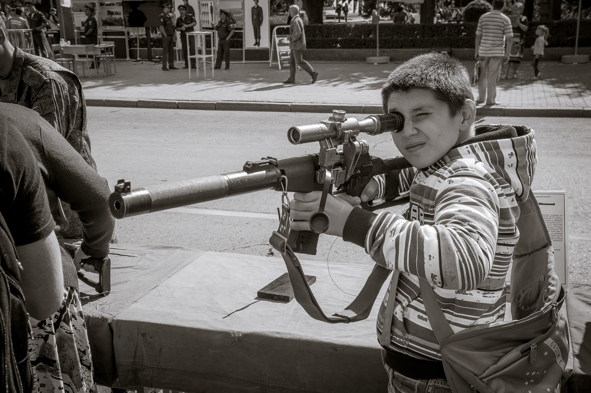 Мальчик целится через прицел снайперской винтовки