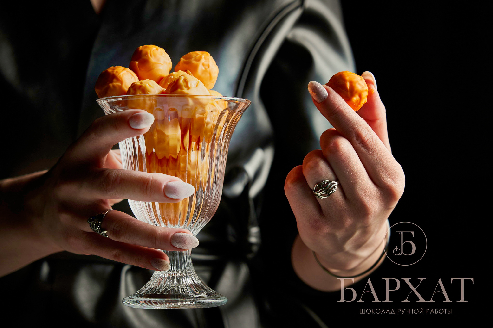 бокал с конфетами в руках девушки в черной куртке