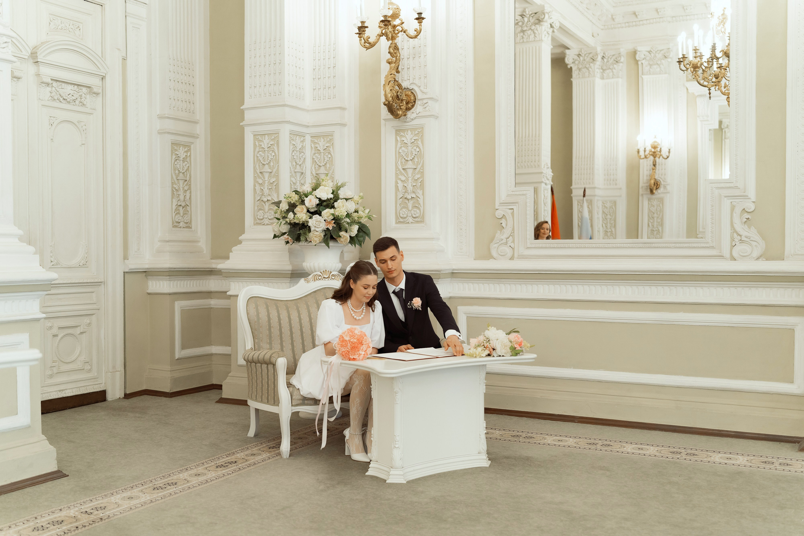 Молодожёны подписывают документы в светлом зале дворца бракосочетания
