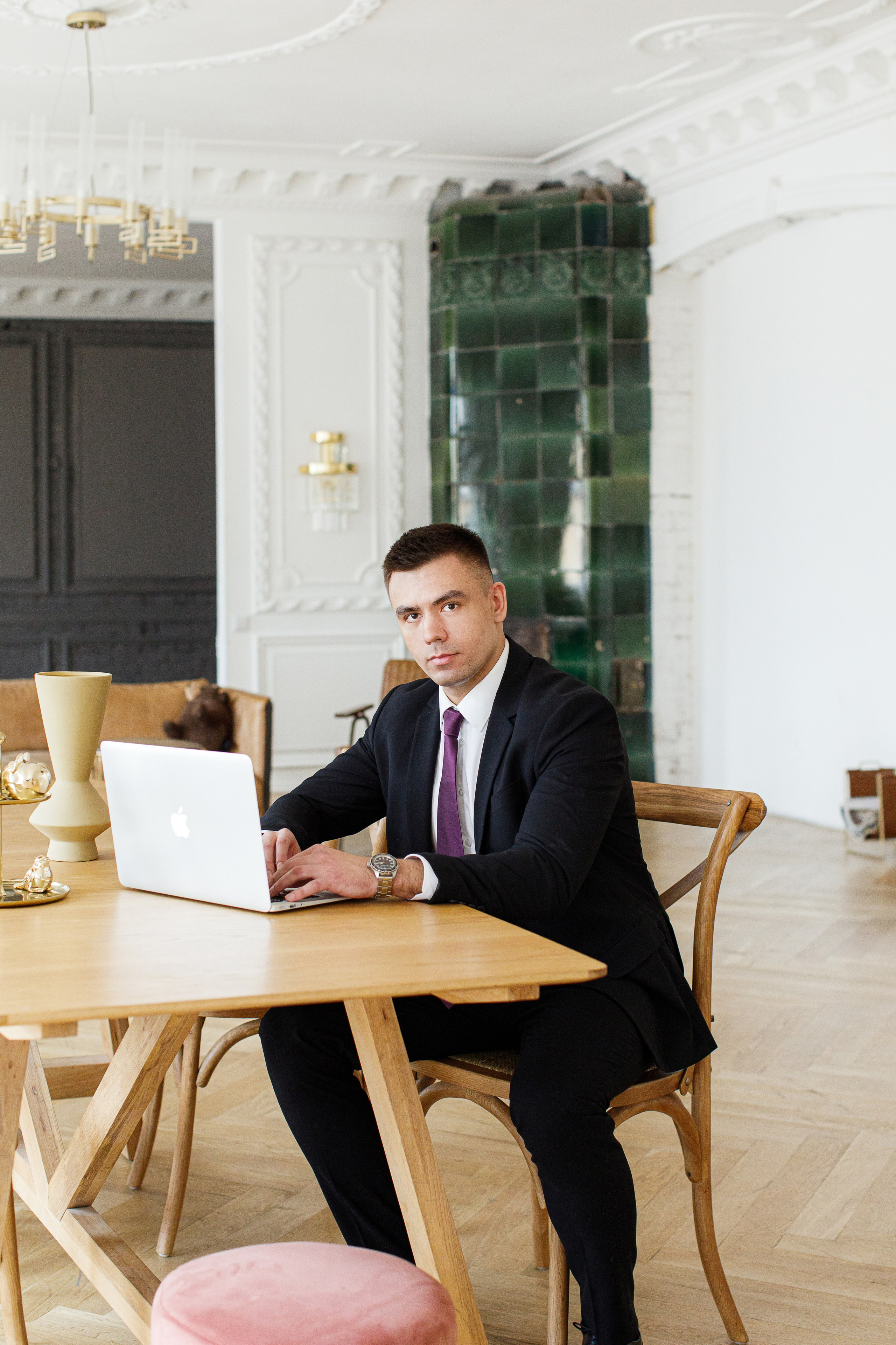 Деловой мужчина в костюме с галстуком сидит за столом с ноутбуком Apple