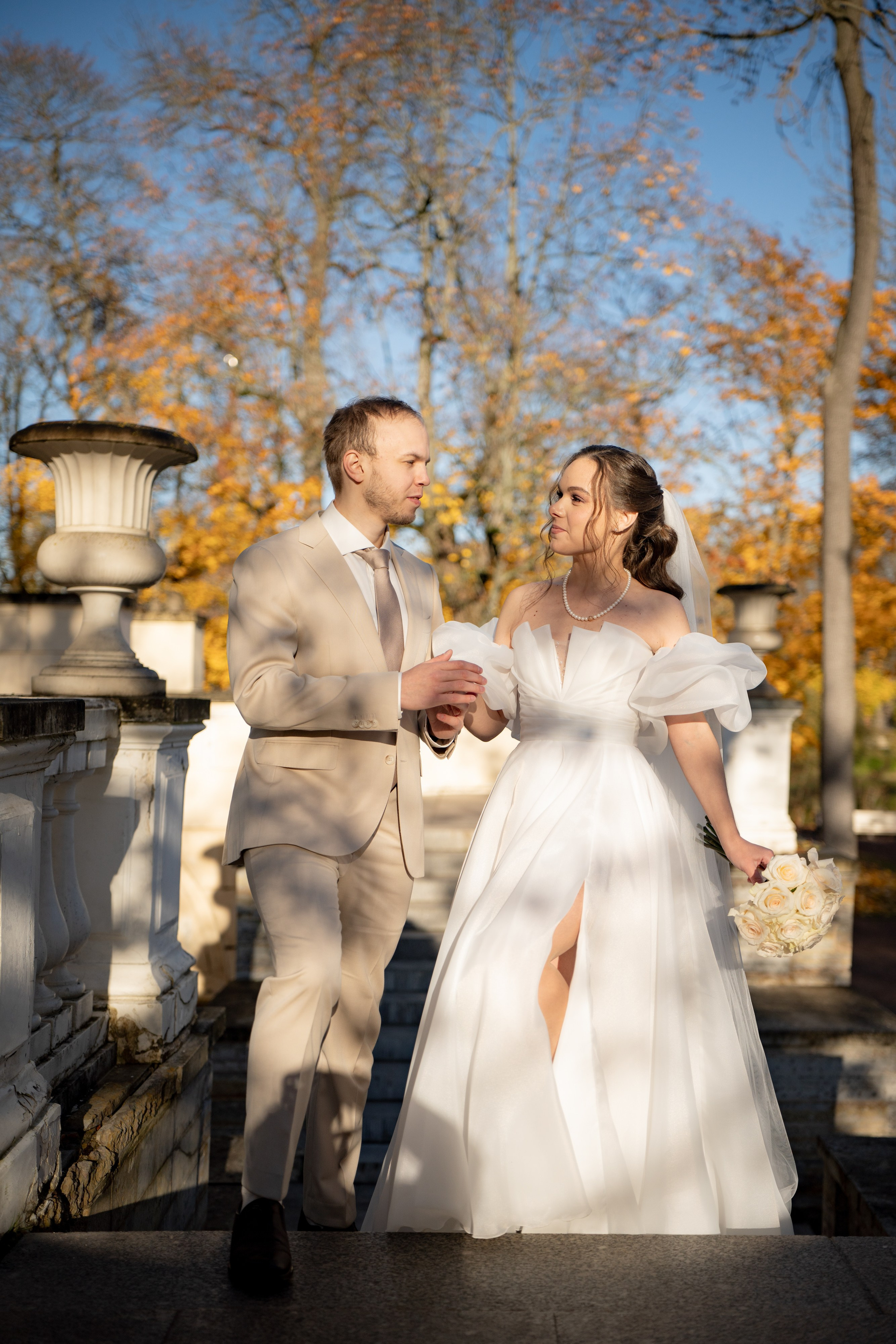 Жених обнимает невесту на крыльце загса в Пушкине в солнечный осенний день