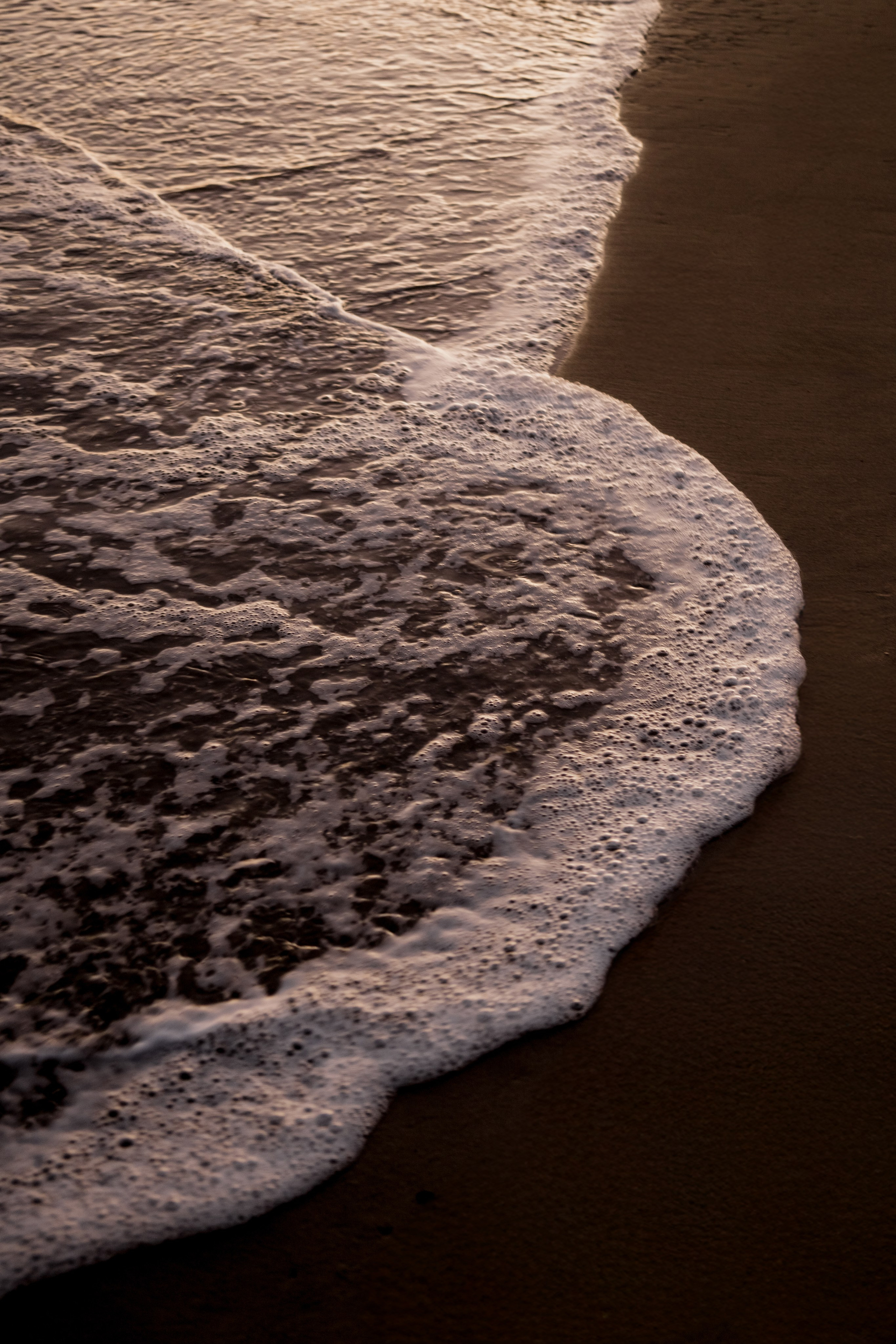 Golden light reflecting off the waves, creating a serene and tranquil beach scene.