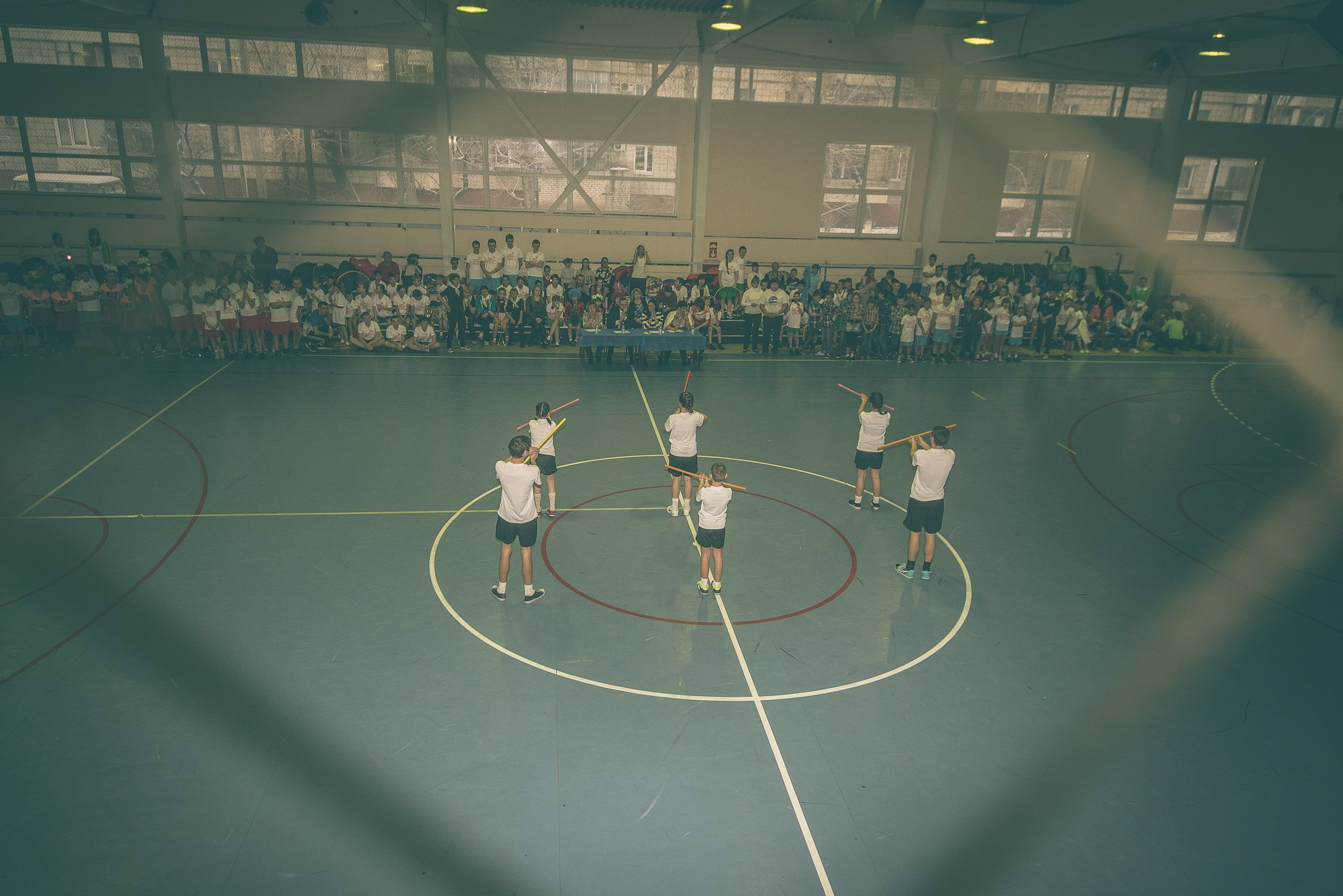 Участники в белых футболках показывают музыкальный номер в спортзале