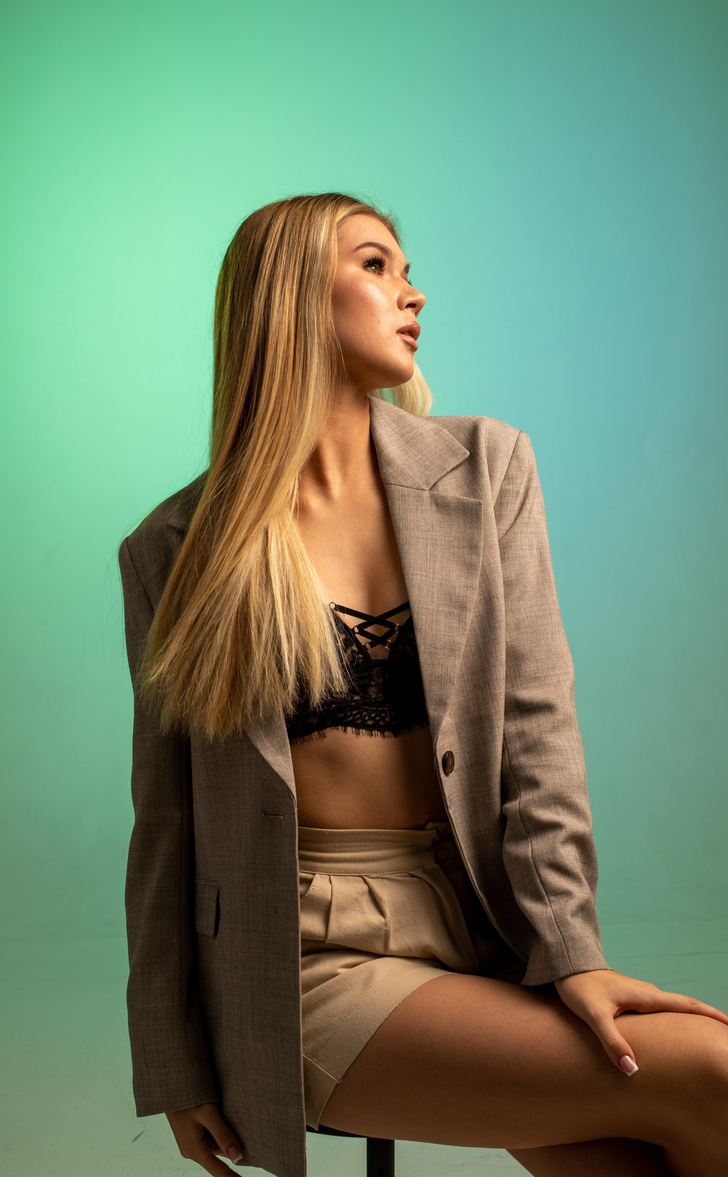 Девушка в фотостудии на бирюзовом фоне в пиджаке и черном топике