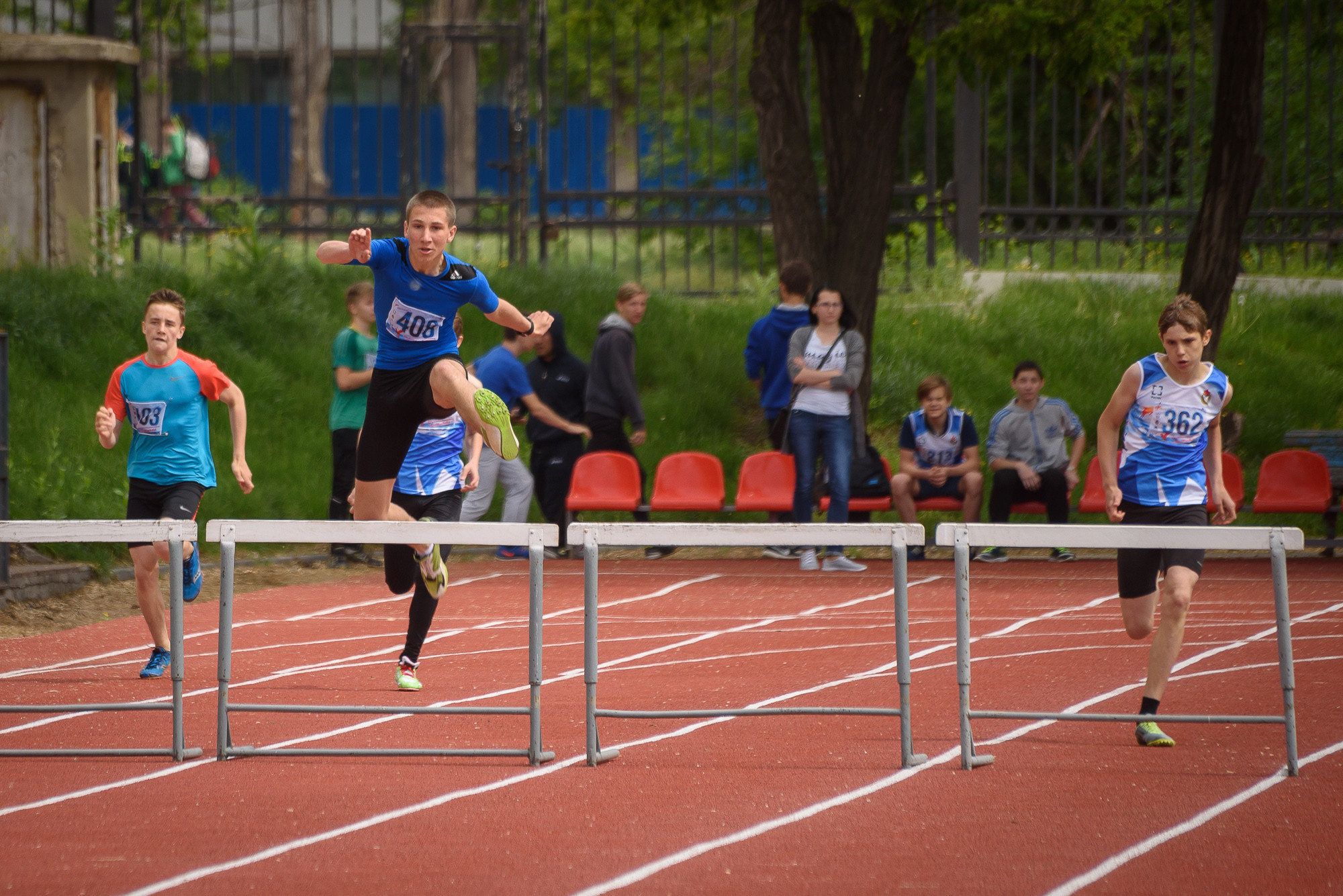 Бегун в синей футболке перепрыгивает барьер во время забега