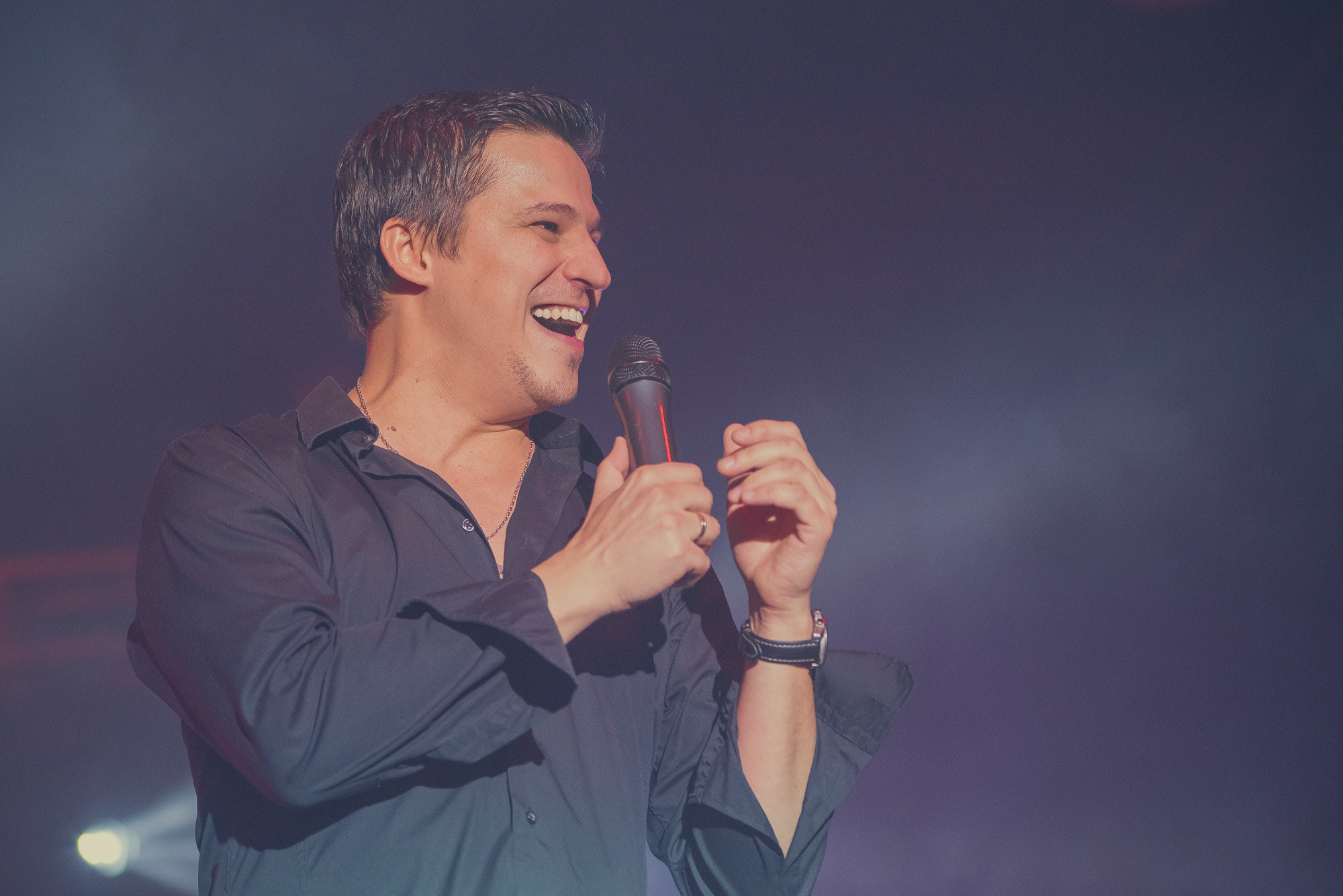 Певец улыбается на сцене во время исполнения своей песни