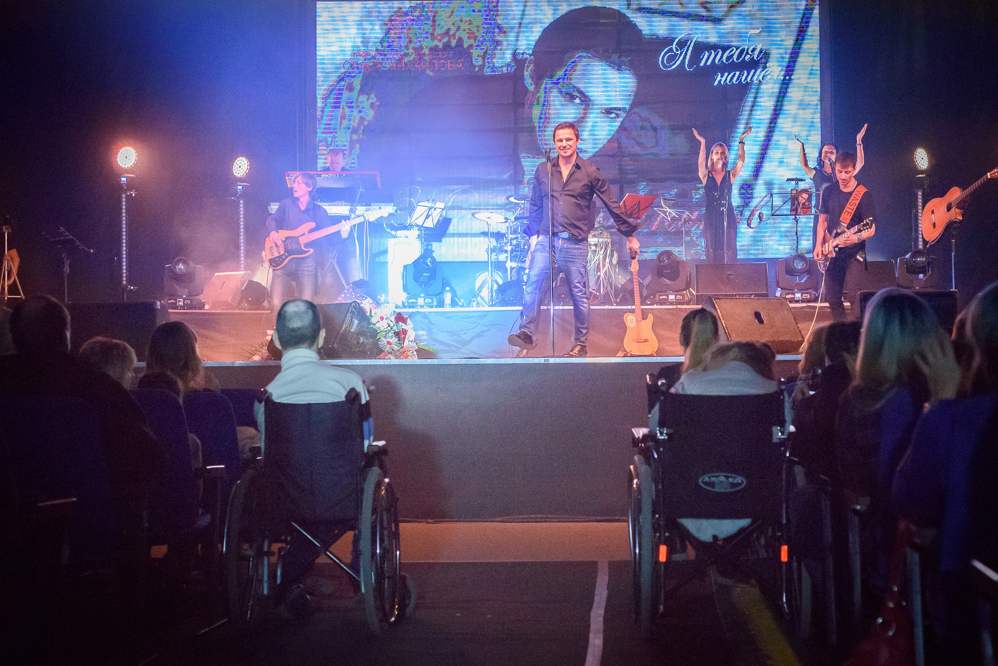 Зрители в инвалидных креслах сидят в зрительном зале во время сольного концерта Максима Олейникова в Волгограде
