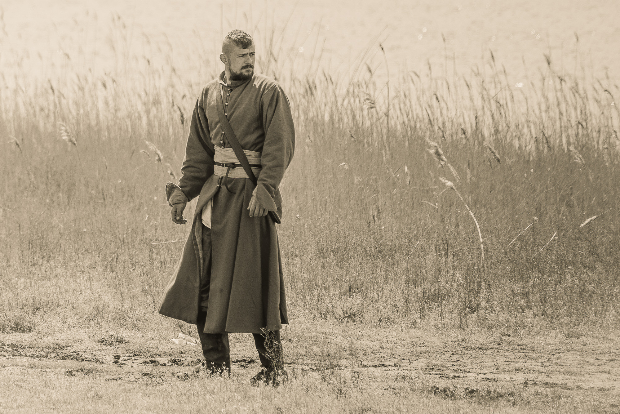 Мужчина в старинном кафтане стоит на фоне камышей