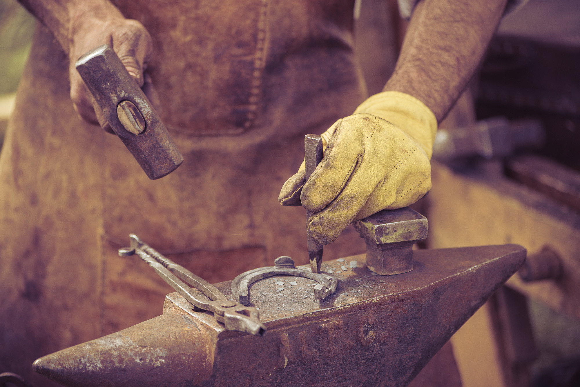 Кузнец стучит молотком по зубилу