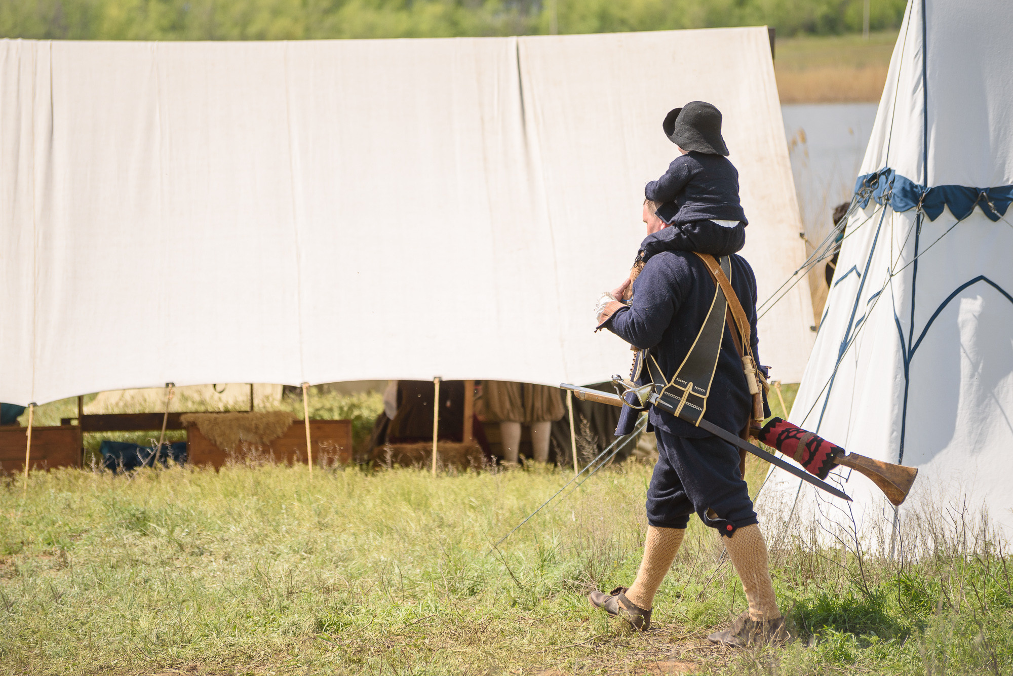 Мужчина в черном костюме несет ребёнка на плечах