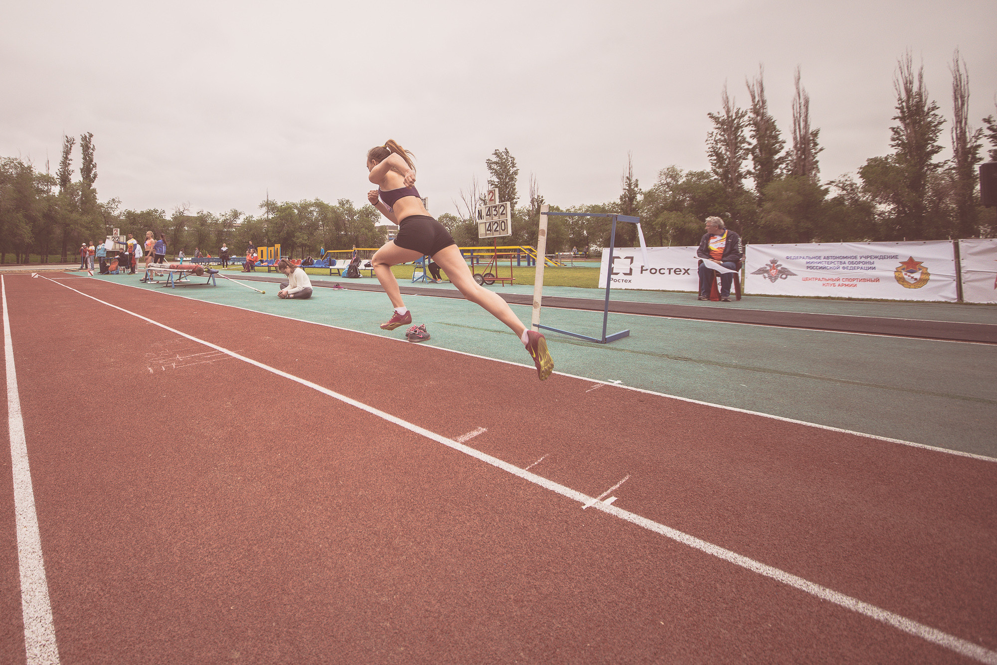 Спортсменка в чёрном костюме разбегается для тройного прыжка