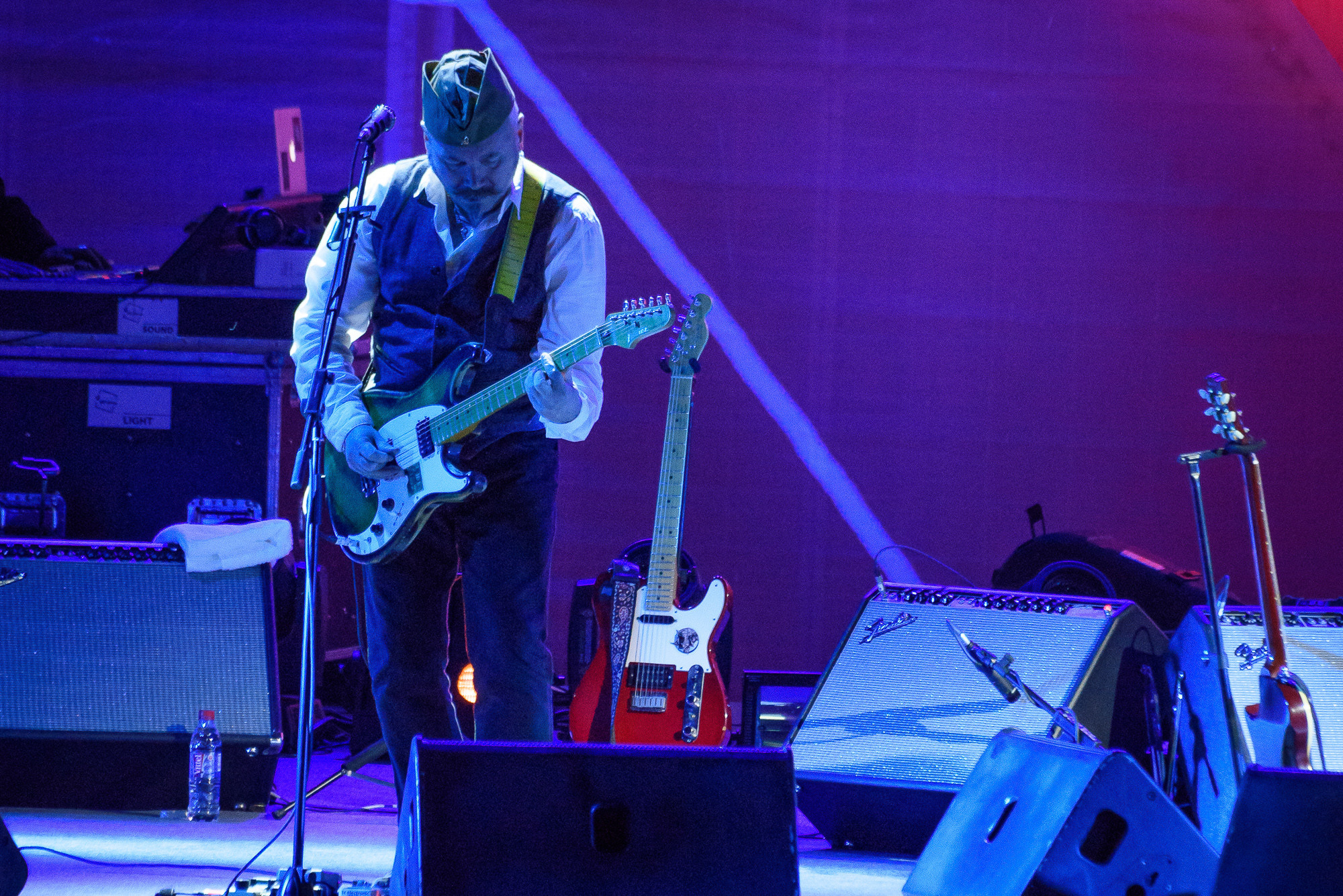 Участник группы Чайф Владимир Бегунов с гитарой на сцене в синем свете