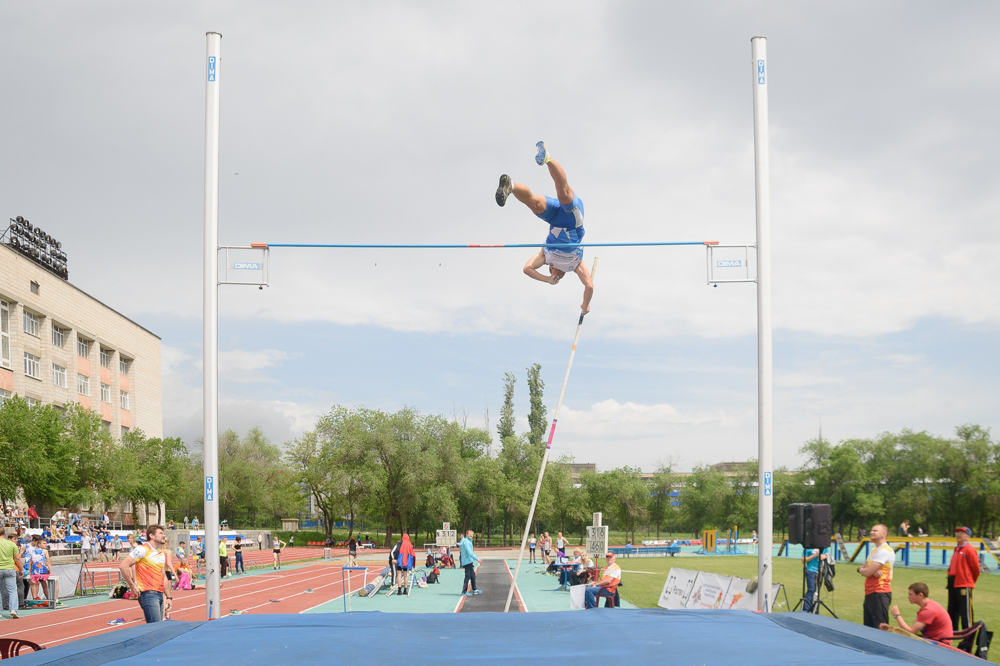 Прыгун с шестом в полете над планкой