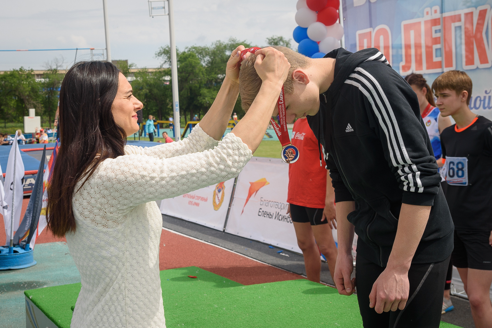 Елена Исинбаева вешает медаль победителю соревнований