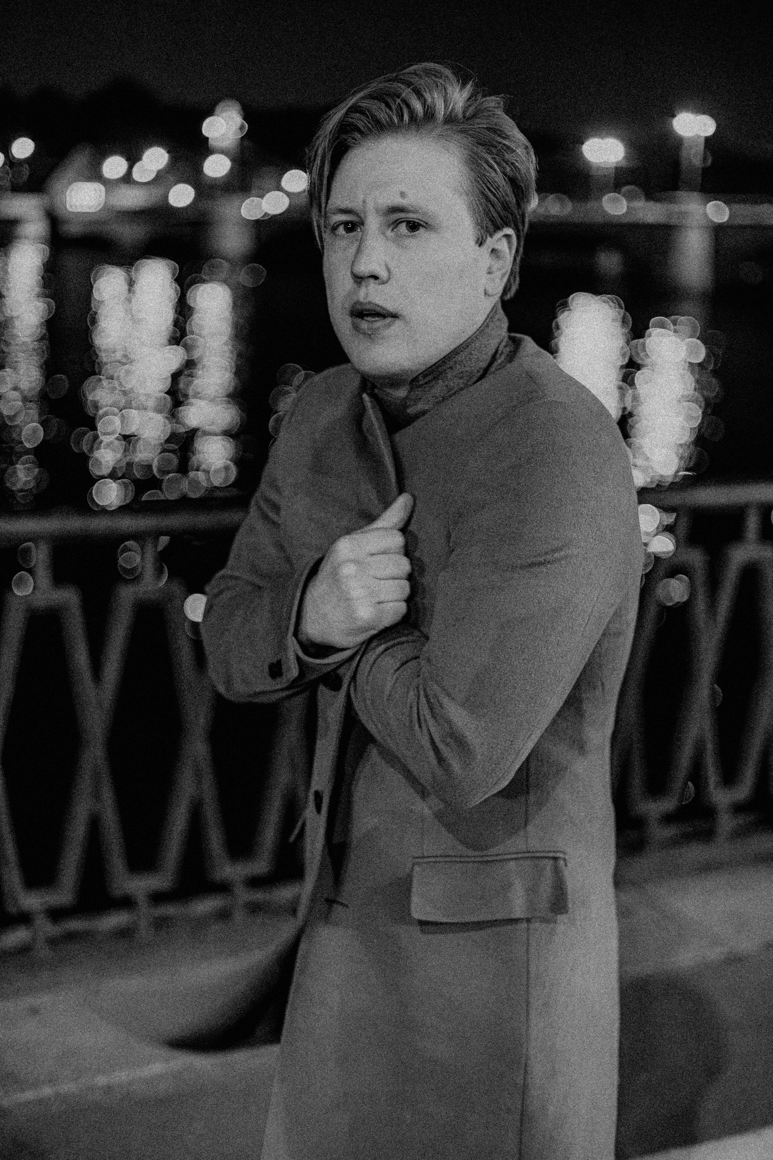 Поэт укутывается в пальто на набережной ночью один.